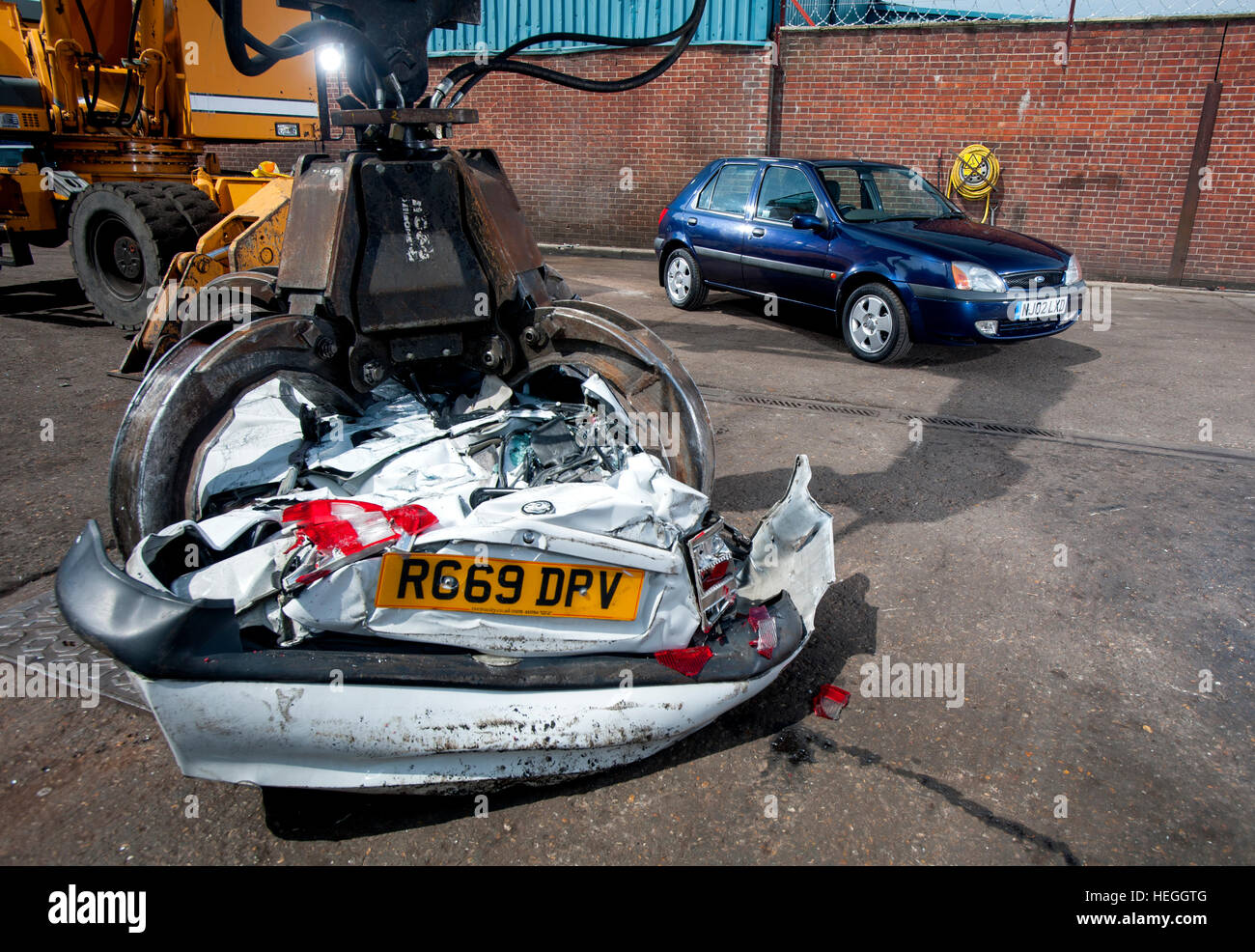 Mâchoires de la mort - un crushedVauxhall 442 dans la griffe d'un parc à ferrailles lors d'une grue, une cour breakers Ford Fiesta attend le même Banque D'Images