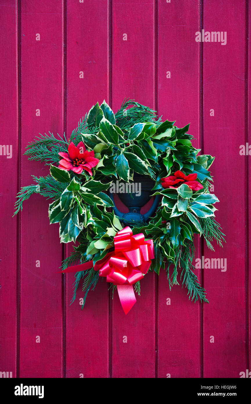 Couronne de Noël sur une porte en bois de couleur rouge, en Angleterre. Banque D'Images