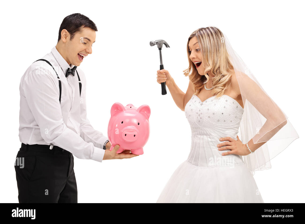Un jeune groom holding piggybank avec une épouse qui s'apprête à casser avec un marteau isolé sur fond blanc Banque D'Images