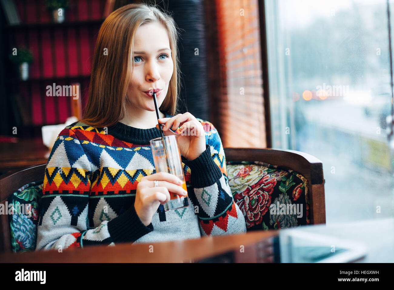 Photo d'une femme boire du jus d'une fenêtre Banque D'Images