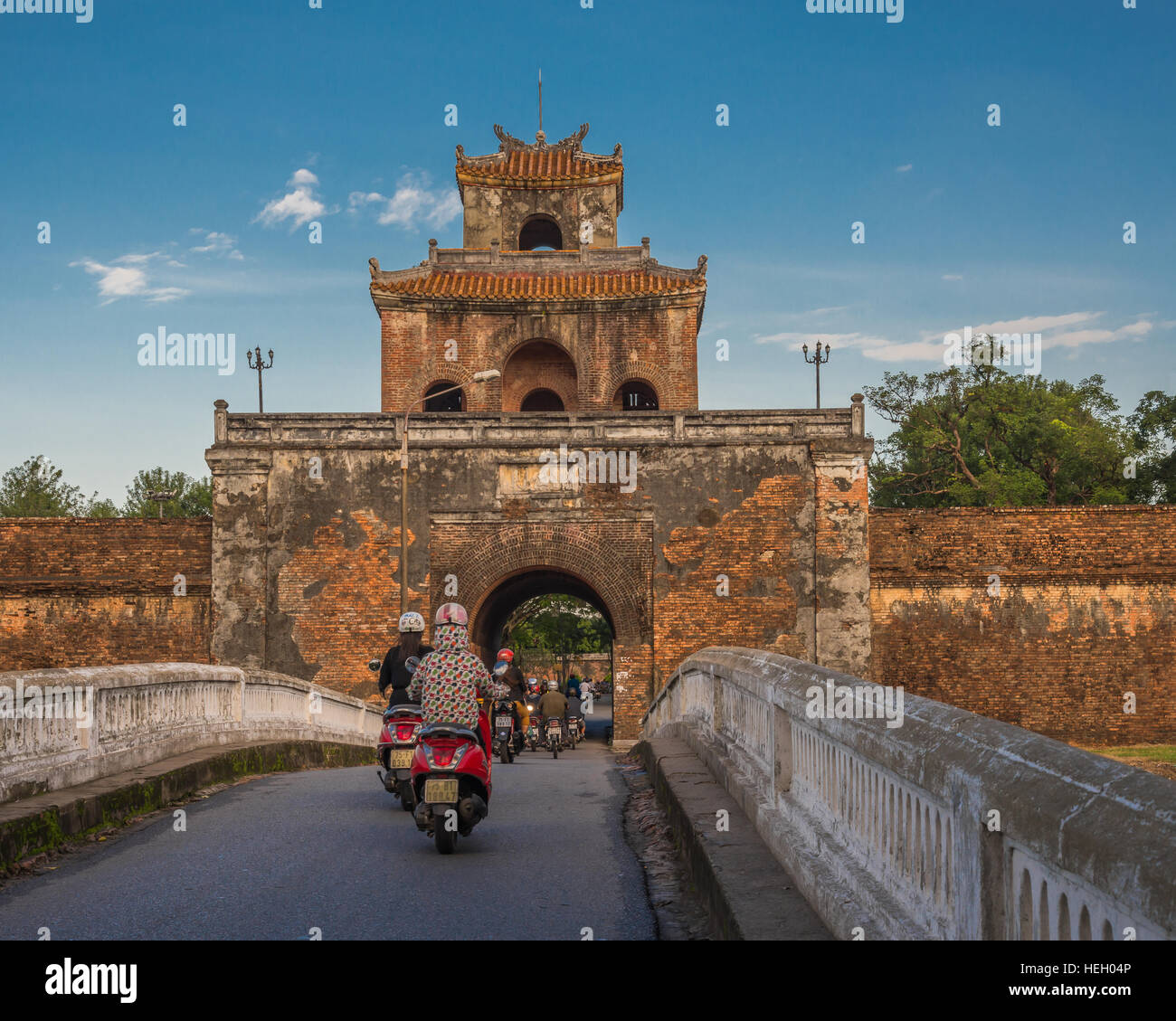La position des scooters sur un pont et à travers l'imposante entrée de la citadelle impériale de Hue, Vietnam Banque D'Images