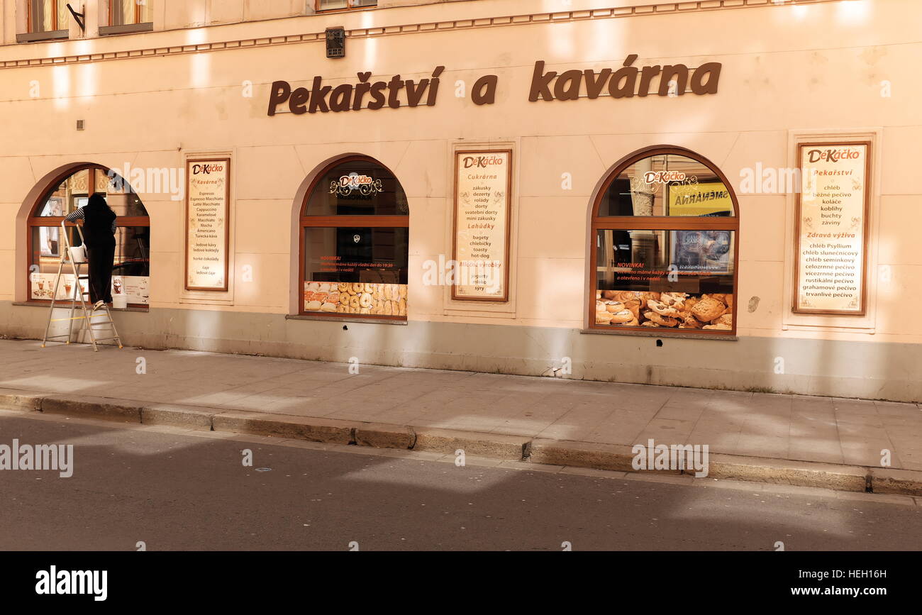 Une femme a lavé les fenêtres d'une boulangerie et d'une boutique de cafés au coucher du soleil à Ceske Budejovice, en République tchèque, en 2016 Banque D'Images