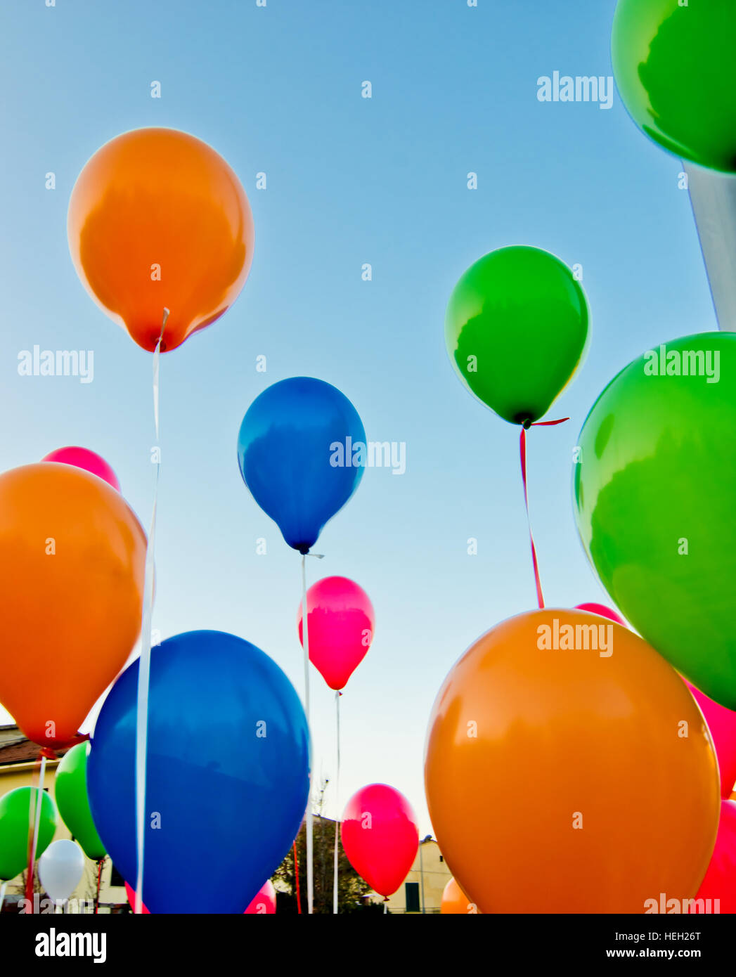 De nombreux ballons colorés lancé à partir de la les enfants heureux volant dans le ciel bleu Banque D'Images