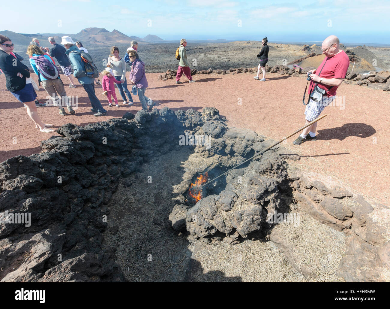 Les touristes regarder broussailles brûler dans un évent volcanique dans le Parc National de Timanfaya, Montañas del Fuego (Montagnes de Feu) dans Lazarote, Canaries, Espagne Banque D'Images