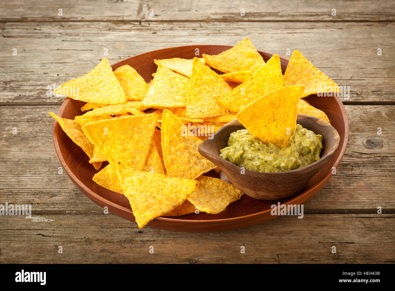 Plaque en bois avec des nachos et Guacamole sur table rustique Banque D'Images