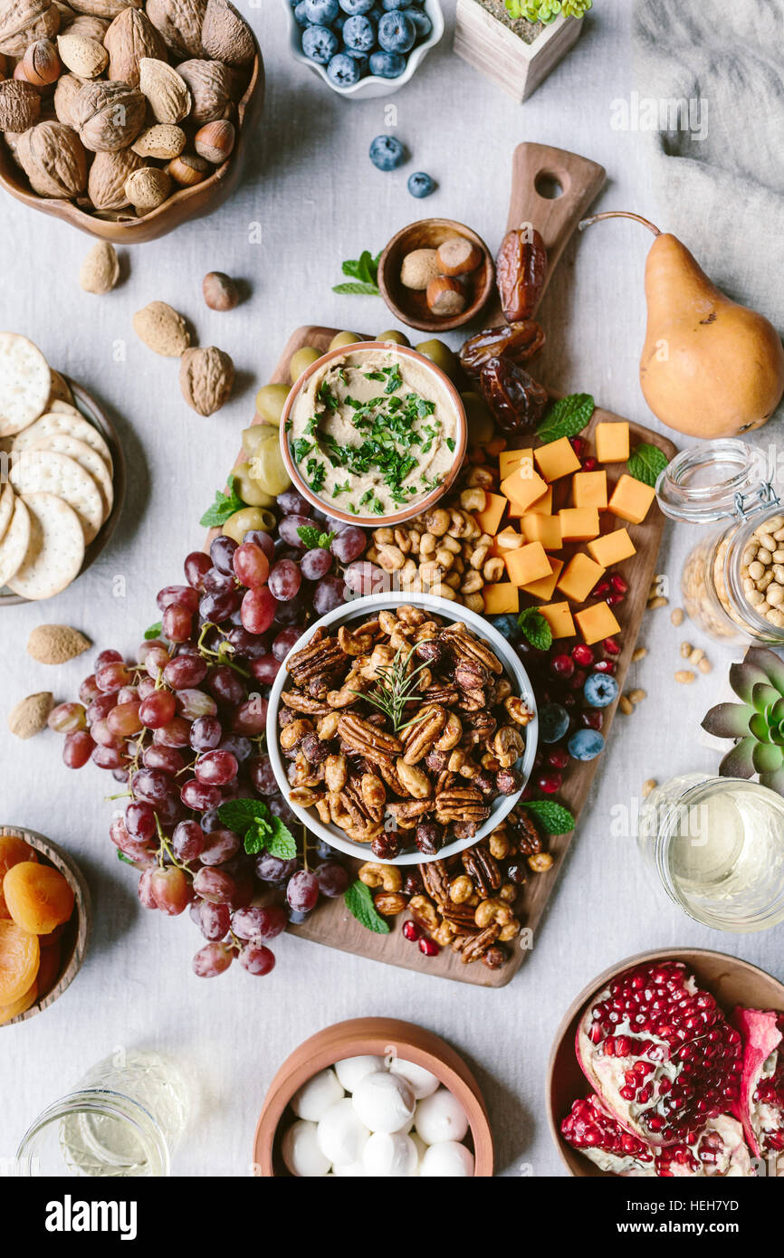 Un bol de pacanes confites épicées sont photographiés dans le cadre d'un conseil de fromages et de fruits. Banque D'Images