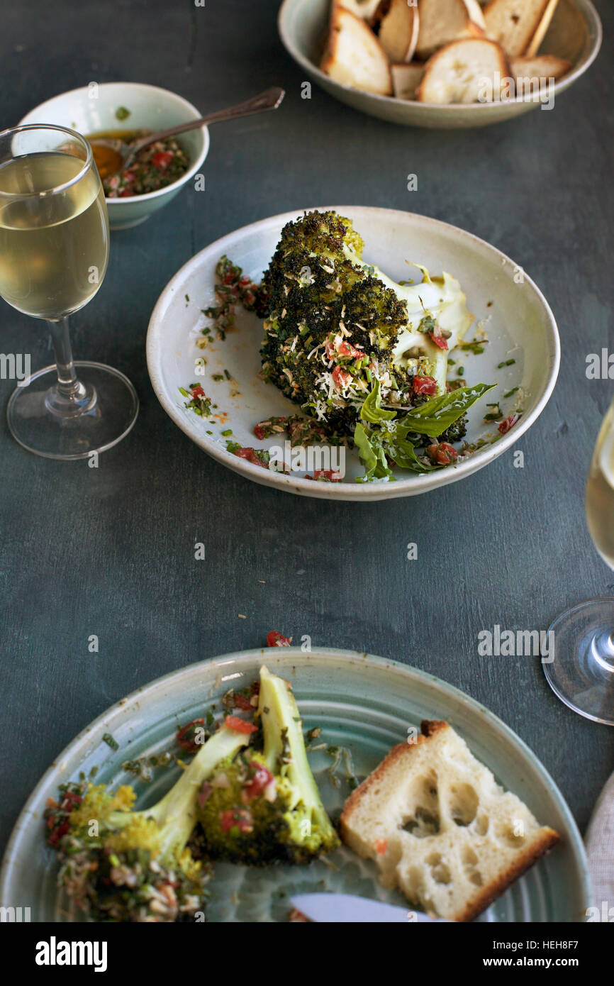 Tête de brocoli blettes à la Tomate sauce verte style italien servi avec pain et vin blanc. Phtographed en vue de dessus sur un fond gris/vert. Banque D'Images