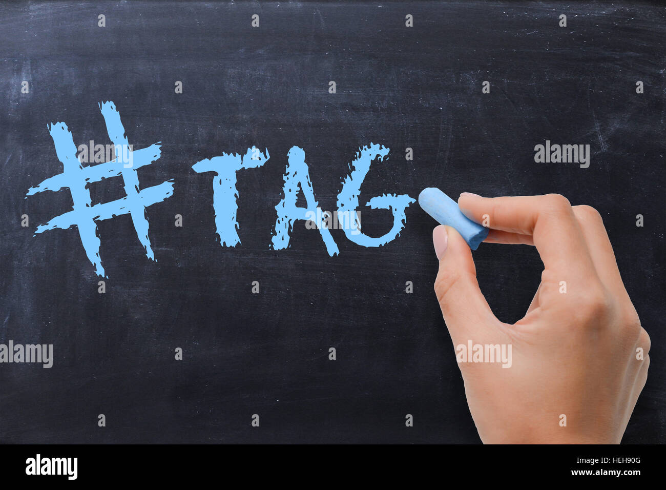 Main femme écrit H tag sur tableau noir avec craie bleu Banque D'Images