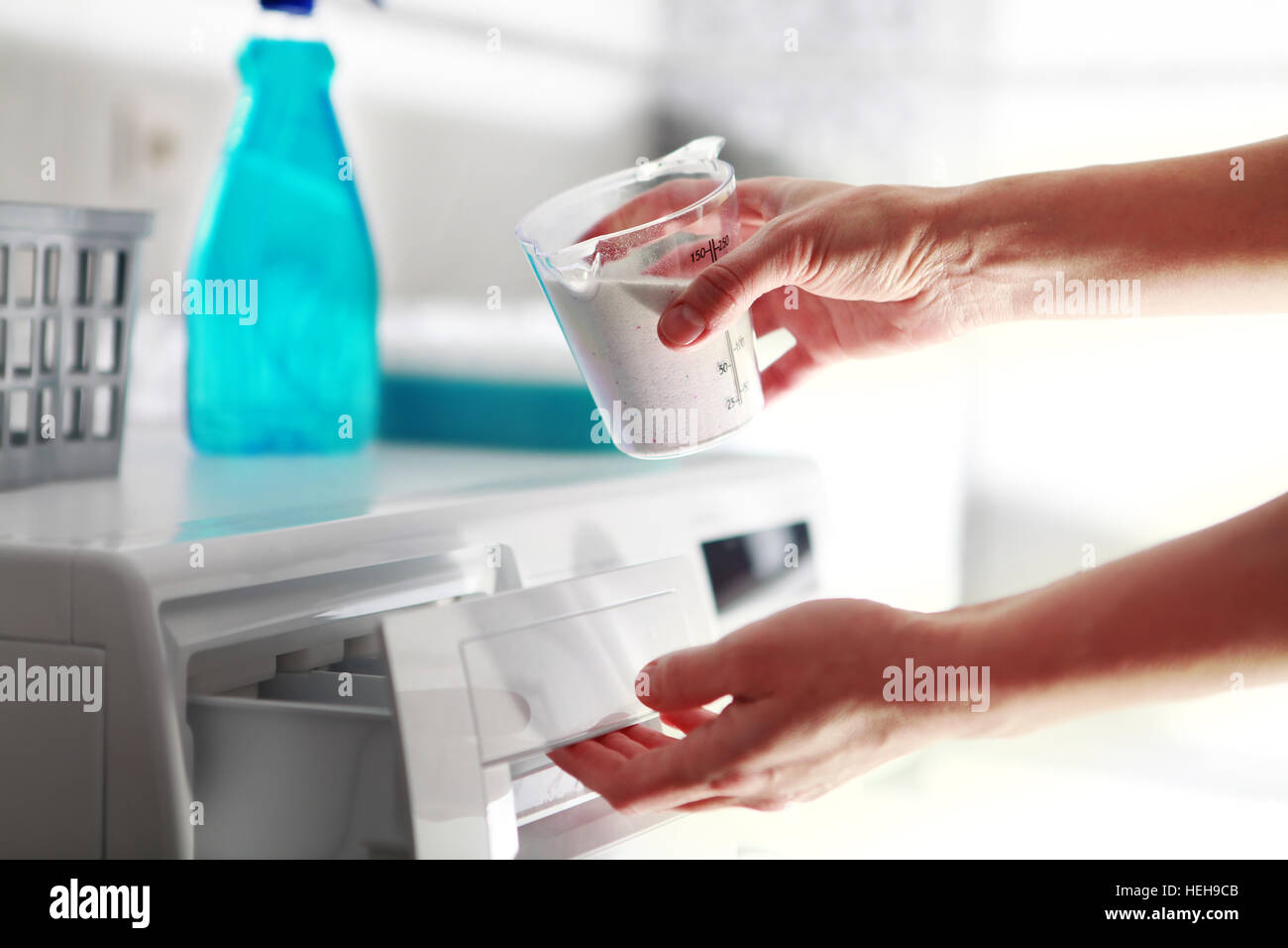 Mains de femme qui remplit de détergent dans la machine à laver Banque D'Images
