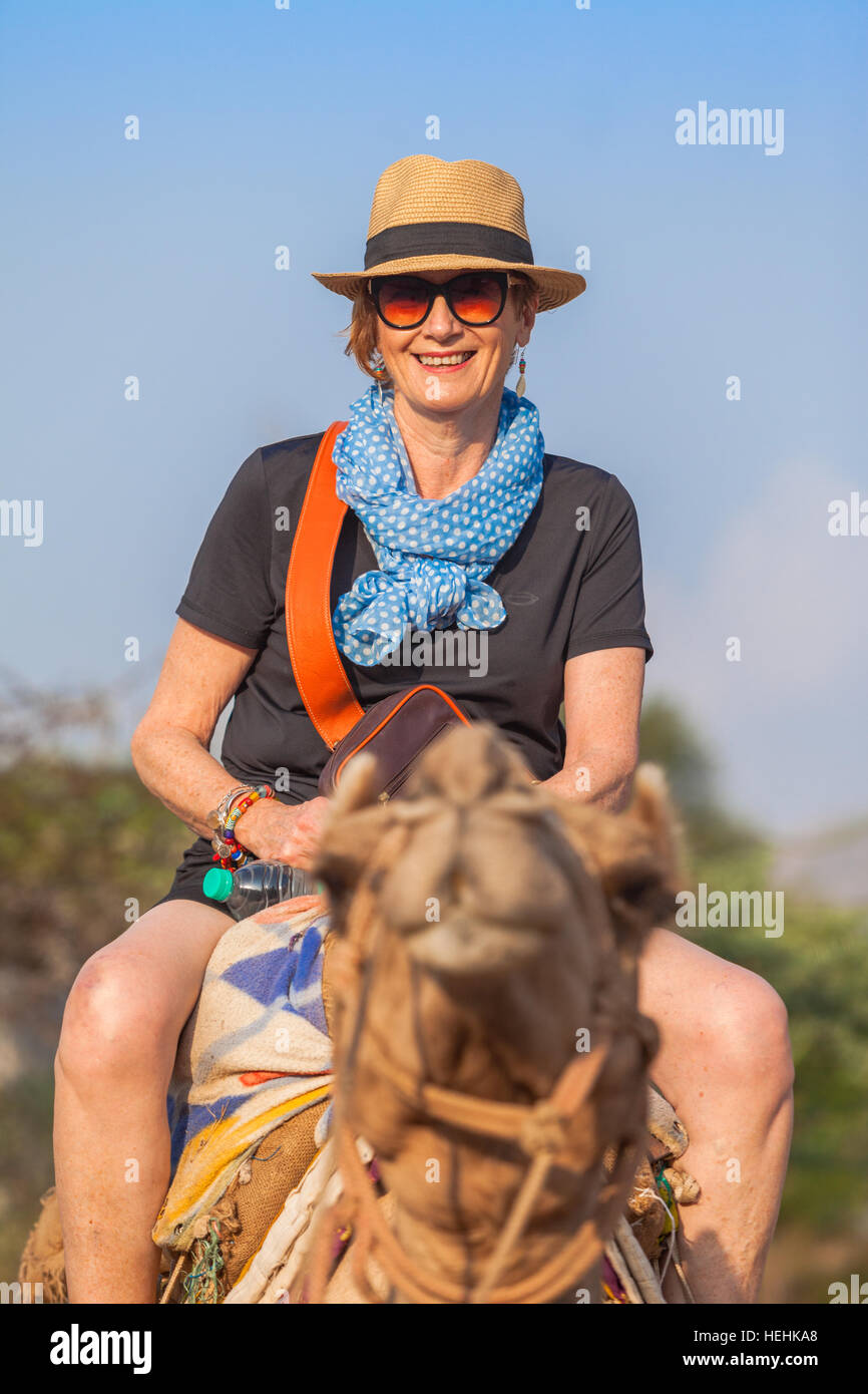 Monté sur un chameau de tourisme dans le nord de l'Inde, femme portant un chapeau et souriant Banque D'Images