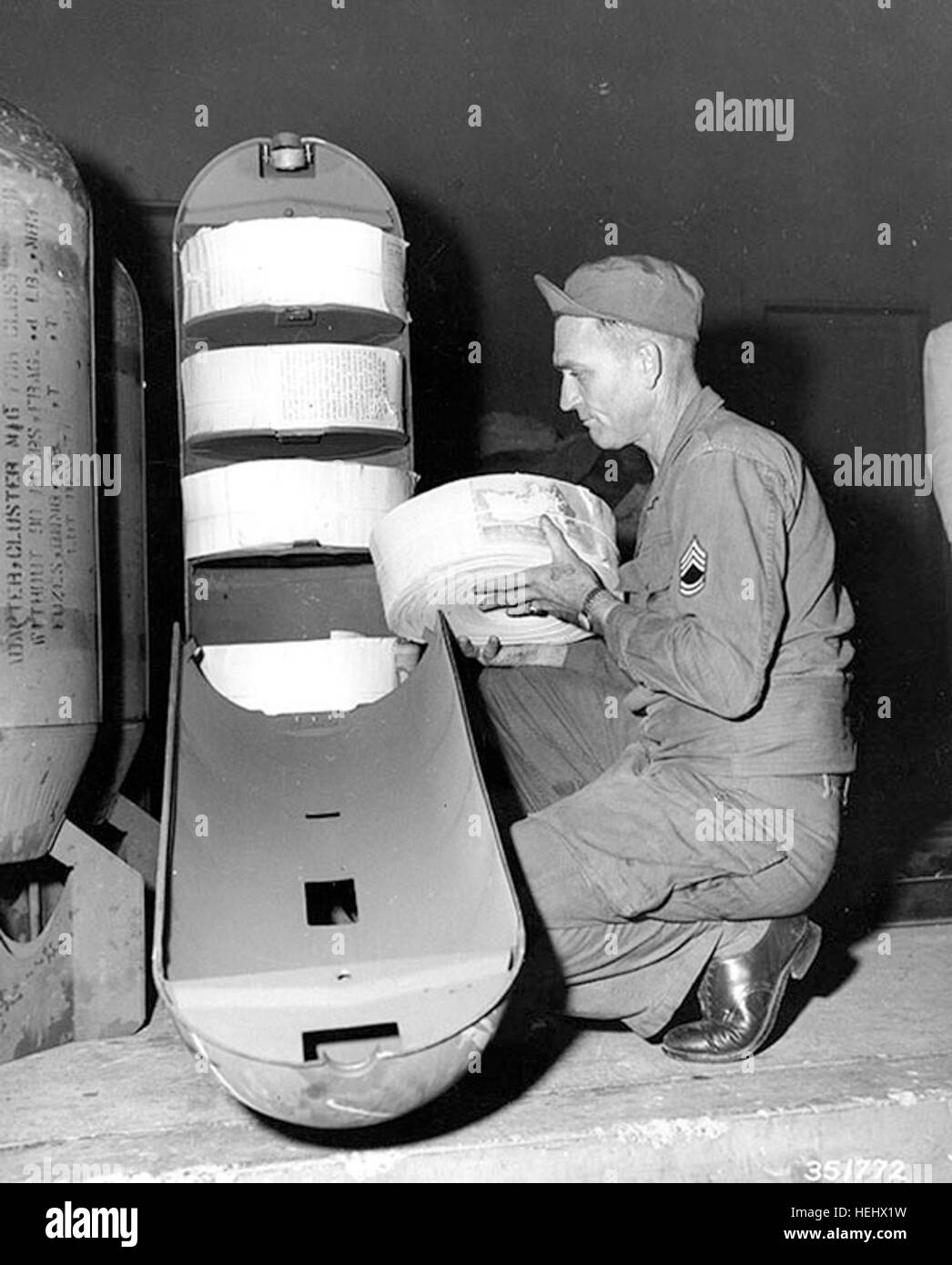 Guerre de Corée Guerre Psychologique Furl SFC A. Krebs charge un M16M1 adaptateur de cluster à la FEC {} loin du commandement de l'atelier d'impression, Yokohama, Japon. L'adaptateur de type bombe contiendra 22 500 (5' x 8') guerre psychologique de dépliants. 1 novembre 1950. Guerre de Corée notice bomb Banque D'Images