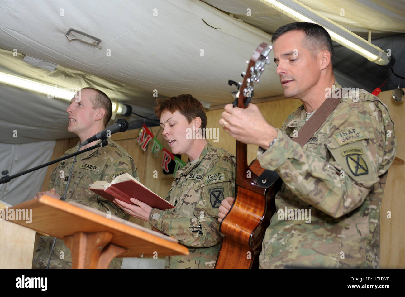 La province de Logar, Afghanistan - à partir de la droite de l'armée américaine, le Lieutenant-colonel Anthony Coston, commandant du 94e Bataillon de soutien de la Brigade, 4e Brigade Combat Team, 10e division de montagne de Little Rock et Hot Springs, Arche, le capitaine de l'armée américaine, Renée Michel, commandant de la Compagnie B, 94e de BSB Dayton, Ohio ; et le capitaine de l'armée américaine Jonathan Spenn, un dentiste de ? ? ? Attribué à la société C, 94e BSB, effectuer un cantique de Noël aux chandelles au cours d'un service sur la base d'opération avancée Shank, l'Afghanistan, la veille de Noël. Ils font partie d'un groupe musical appelé la bande de louange, qui a joué plusieurs chansons au cours de la se Banque D'Images