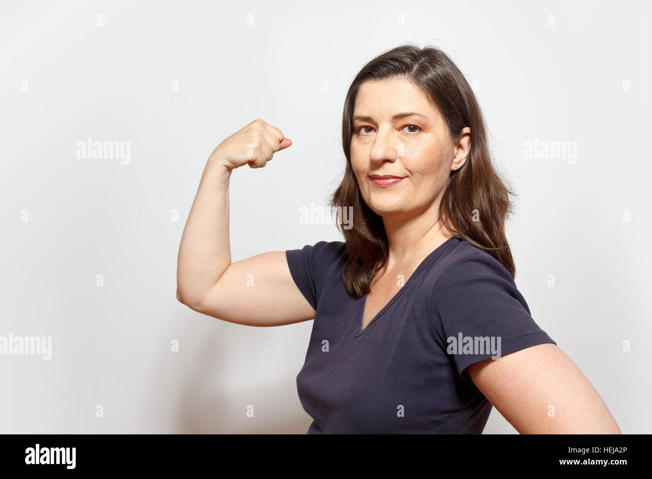 Middle aged woman flexing muscles ses biceps, montrant la confiance en soi et la fierté, fond blanc, copier ou de l'espace texte, copyspace Banque D'Images
