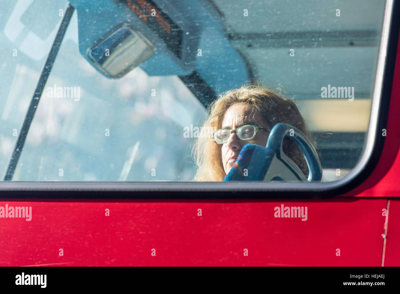 Une femme assise seule à l'avant de la partie supérieure d'un bus à impériale rouge, regarder par la fenêtre, alors qu'elle voyage à travers Londres. Banque D'Images