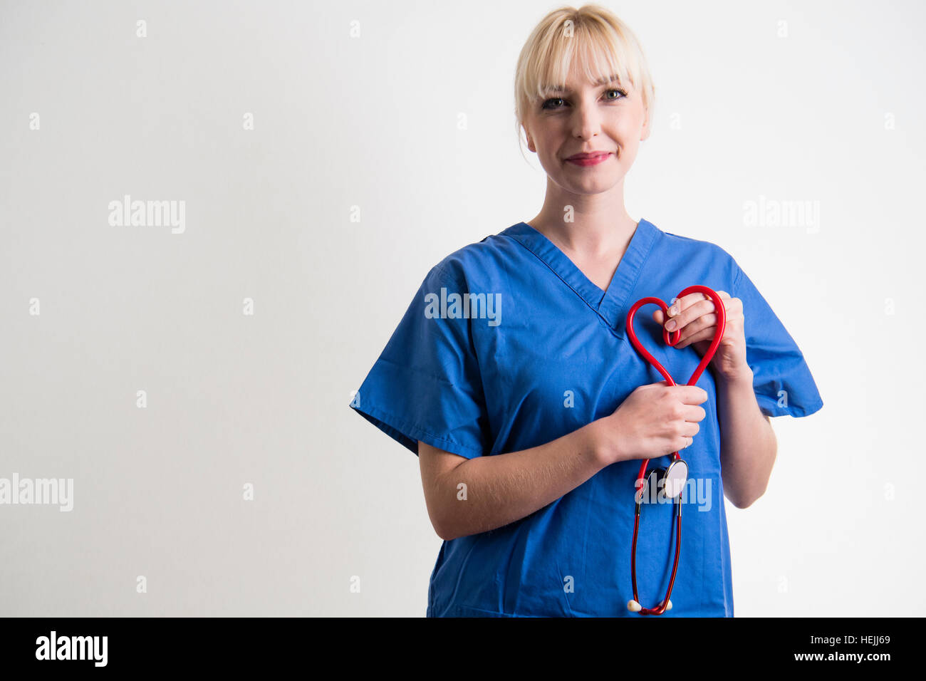 Les professionnels de la Santé du Royaume-Uni : A National Health Service (NHS) femme female nurse holding a stethescope rouge en forme de cœur. Banque D'Images