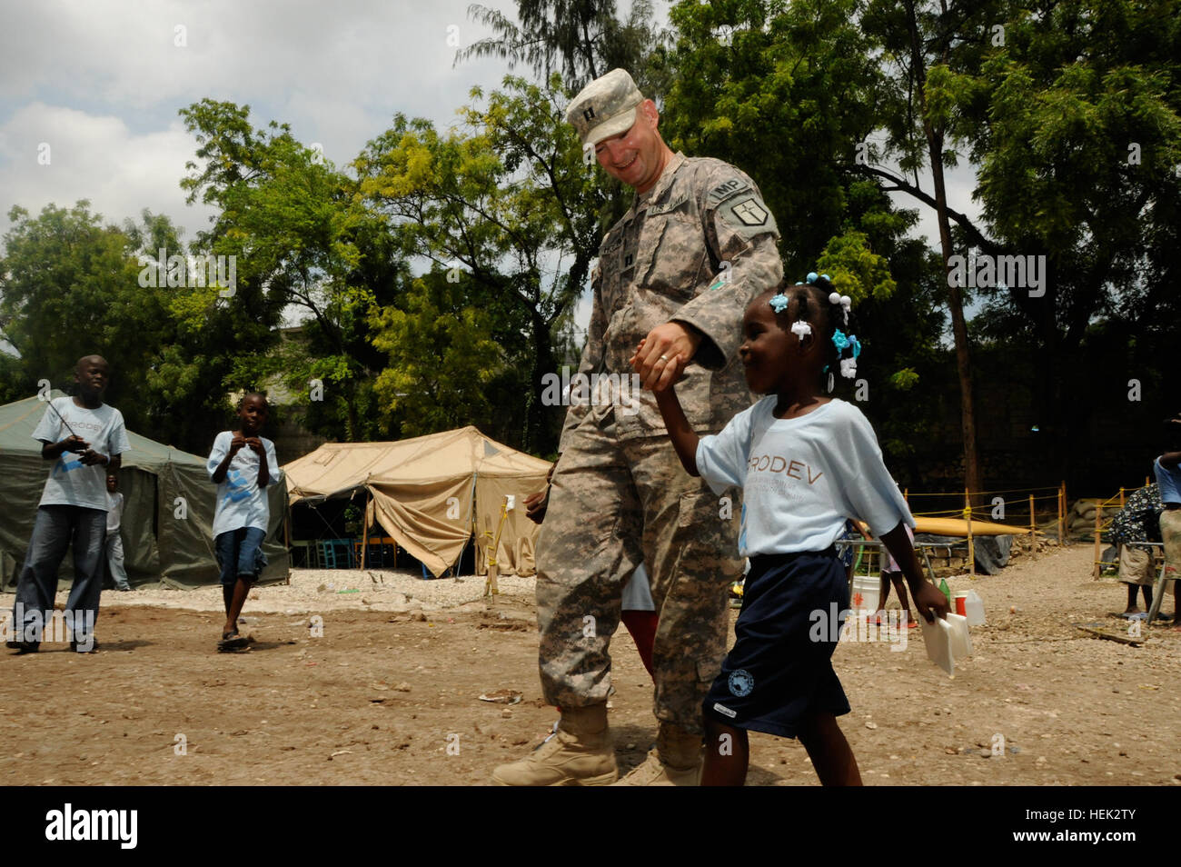 Le capitaine de l'armée américaine, commandant Eric Hoeprich Andrew, 209e Compagnie de Police militaire à Fort Polk, en Louisiane, les promenades le long avec une jeune Haïtienne lors d'une inspection du camp de personnes déplacées de Pétion-ville à Port-au-Prince, Haïti, 26 avril. Le 209e a effectué des opérations de sécurité dans le cadre de l'opération réponse unifiée. L'armée américaine en Haïti 277066 Banque D'Images