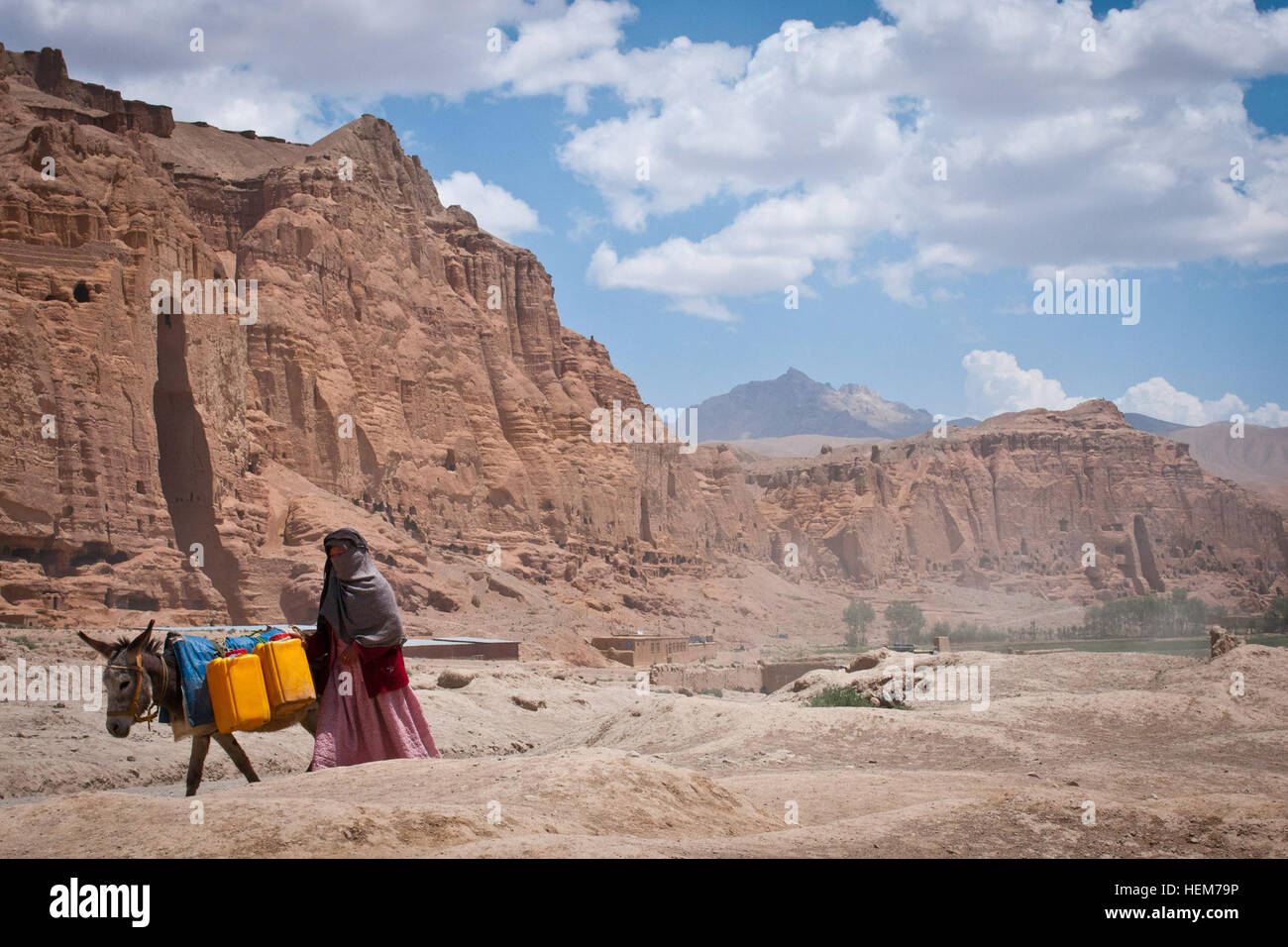 La province de Bamyan, Afghanistan - un âne promenades femmes passé la cavité où l'une des statues antiques, connu sous le nom de Bouddhas de Bamiyan, utilisé pour se tenir le 17 juin 2012. Les statues monumentales ont été construit en 507 et 554 après JC, et étaient les plus grandes statues de Bouddha debout sur la terre jusqu'à ce que les talibans ont dynamité en 2001. Le plus grand, ou 'Père' Bouddha était dans le trou le plus proche et était de 180 pieds de haut, tandis que les plus petites d'autres 'Bouddha', 121 pieds de haut, l'habitude d'être dans le trou vu plus loin dans la vallée. (U.S. Photo de l'armée par le Sgt. Ken cicatrice, Mobile 7e Détachement des affaires publiques) Les gens de Bamyan-5 Banque D'Images