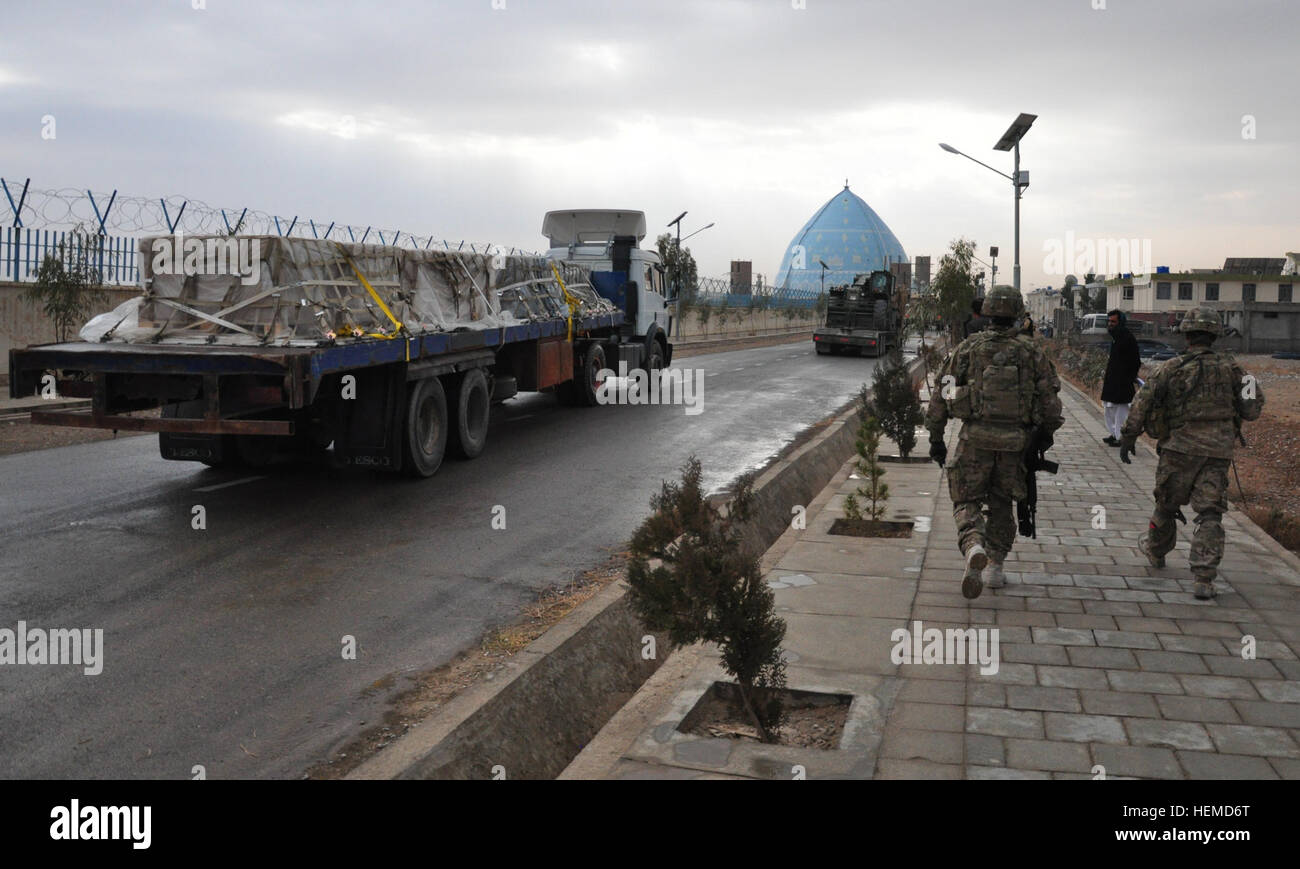 Les membres de l'Équipe de reconstruction provinciale de Kandahar, une équipe civilo-militaire conjointe basée à Camp Nathan Smith, l'Afghanistan, à pied pour rencontrer les représentants de l'Université de Kandahar pour livrer trente-six contenants de panneaux solaires 8 janvier. Un convoi de camions transportés à plat local la charge, ce qui est un don d'entreprise de l'Arizona First Solar Pour l'université. (U.S. Photo de l'armée par le sergent. Jeff Neff/libérés) 130108-A-KI132-426 Banque D'Images