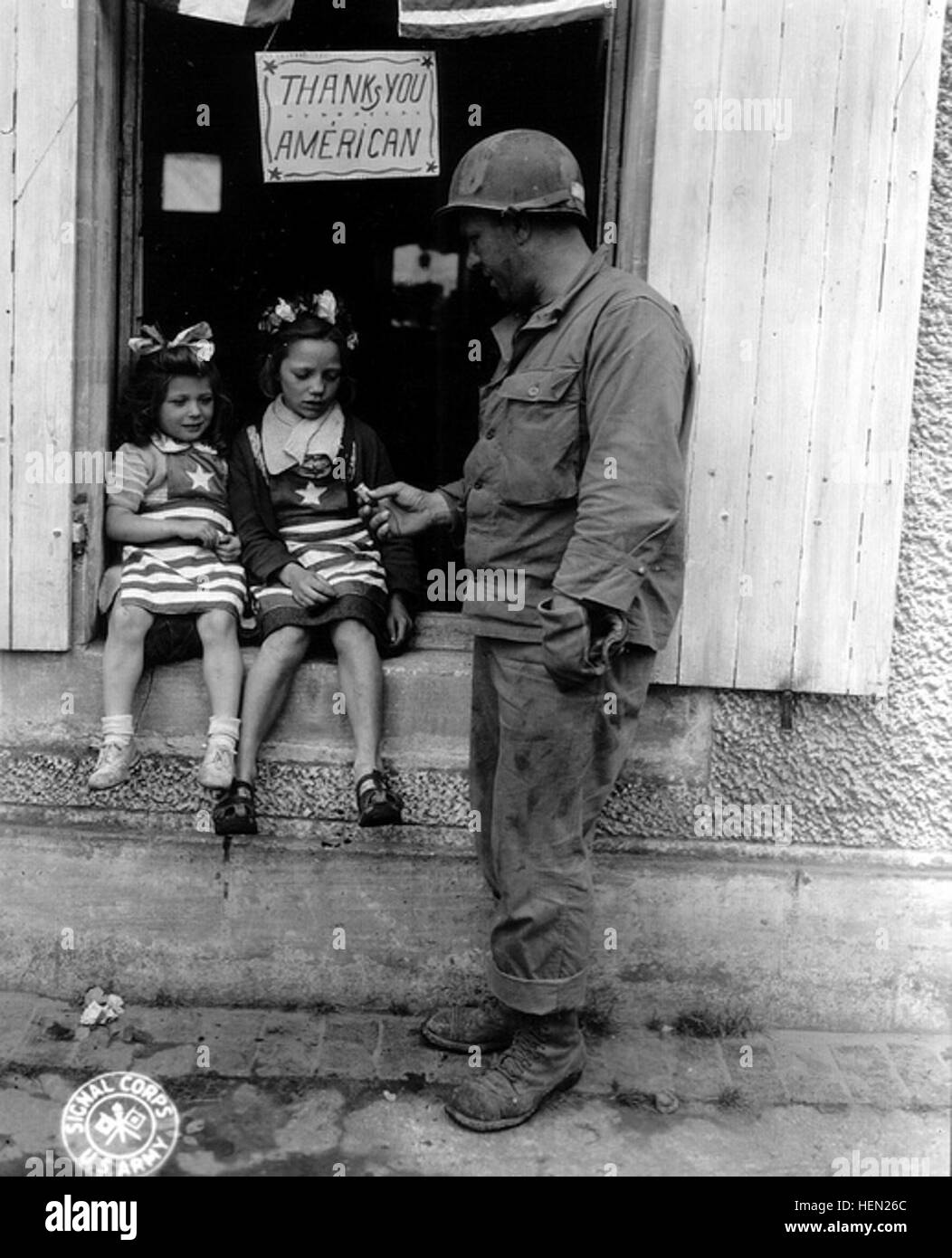 Deux petites filles habillées aux couleurs des libérateurs découvrent le chewing-gum que leur tend un sous officier US dont le casque M1 est camouflé (boue ou produit vésicant) Une pancarte est affichée à la fenêtre avec l'inscription 'américain' vous remercie (le s de "merci a été ajouté après-coup...) ' Merci aux Américains ' D'après la page 89 de : La Manche libérée, Michel Boivin, Vincent Corbrion, 1944-1994, 50e anniversaire du débarquement, imprimerie Corbrion Http://www.flickr.com/photos/mlq/4271760462/, 1994 : Il s'agit du sergent Walter P Goworek de Jersey City, New Jersey. Selon ce site : http :/ Banque D'Images