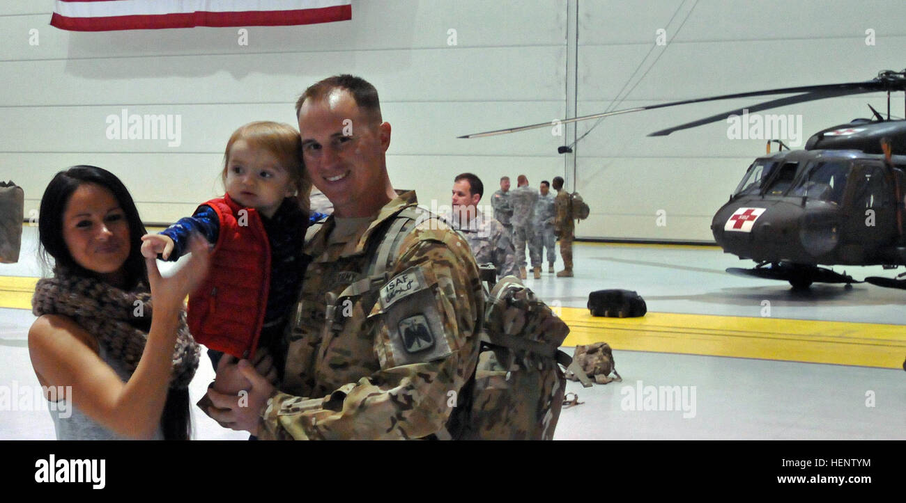 CW2 Daniel Herrington embrasse sa femme, Bretagne, et leur fils âgé de 16 mois, Wylder, après une cérémonie de redéploiement lieu à Fort Wainwright Le hangar 6 29 septembre, 2014. Harrington est affecté au 1er Bataillon, 52e Régiment d'aviation, qui revient d'un vol d'évacuation médicale de déploiement de missions en Afghanistan. (U.S. Photo de l'armée par le Capitaine Matt Baldwin, Affaires publiques/USARAK) Parution de l'Alaska de la guerre retour experts medevac 140929-A-IQ085-791 Banque D'Images