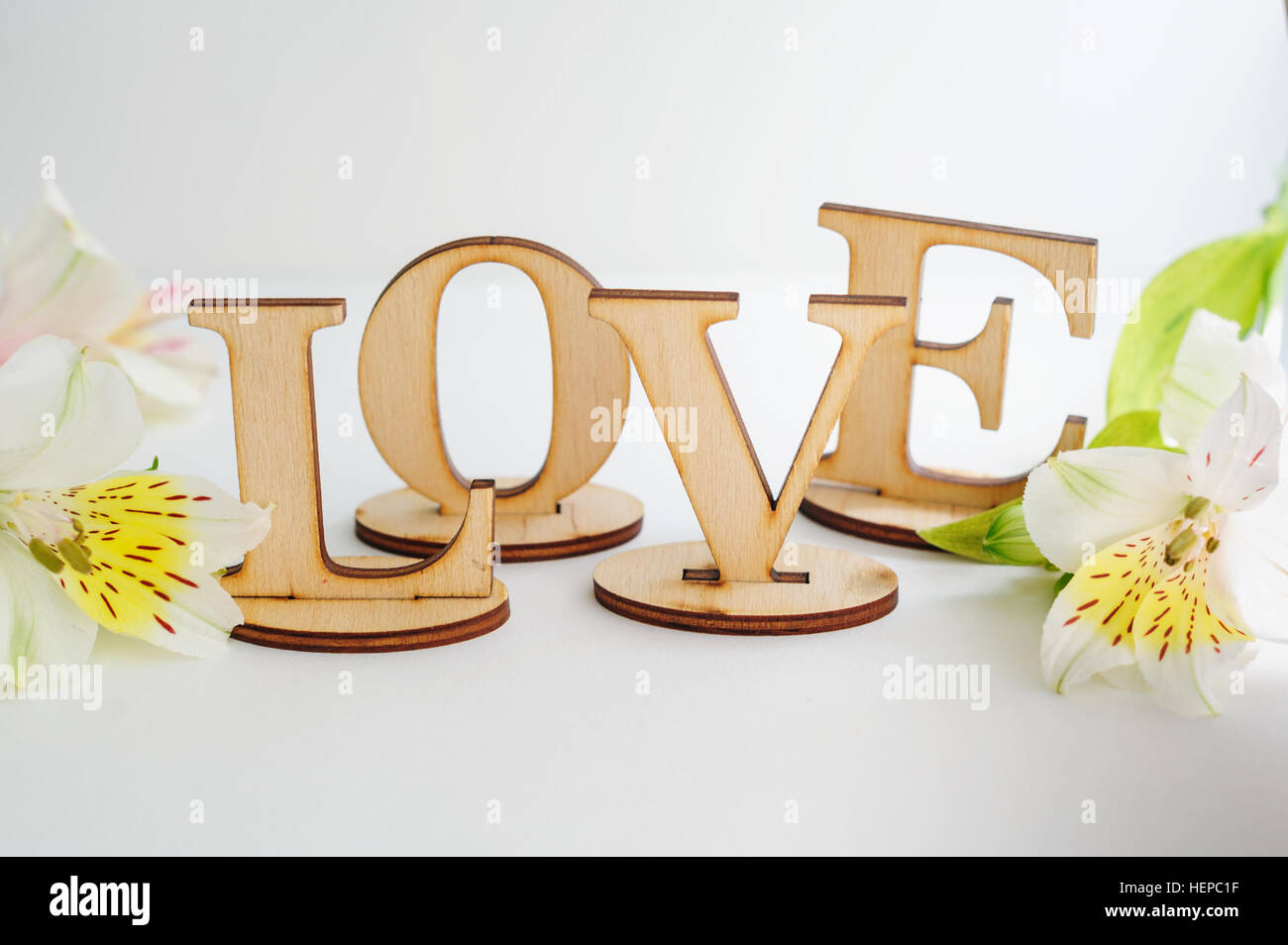 L'amour des lettres en bois avec des fleurs sur fond blanc Banque D'Images
