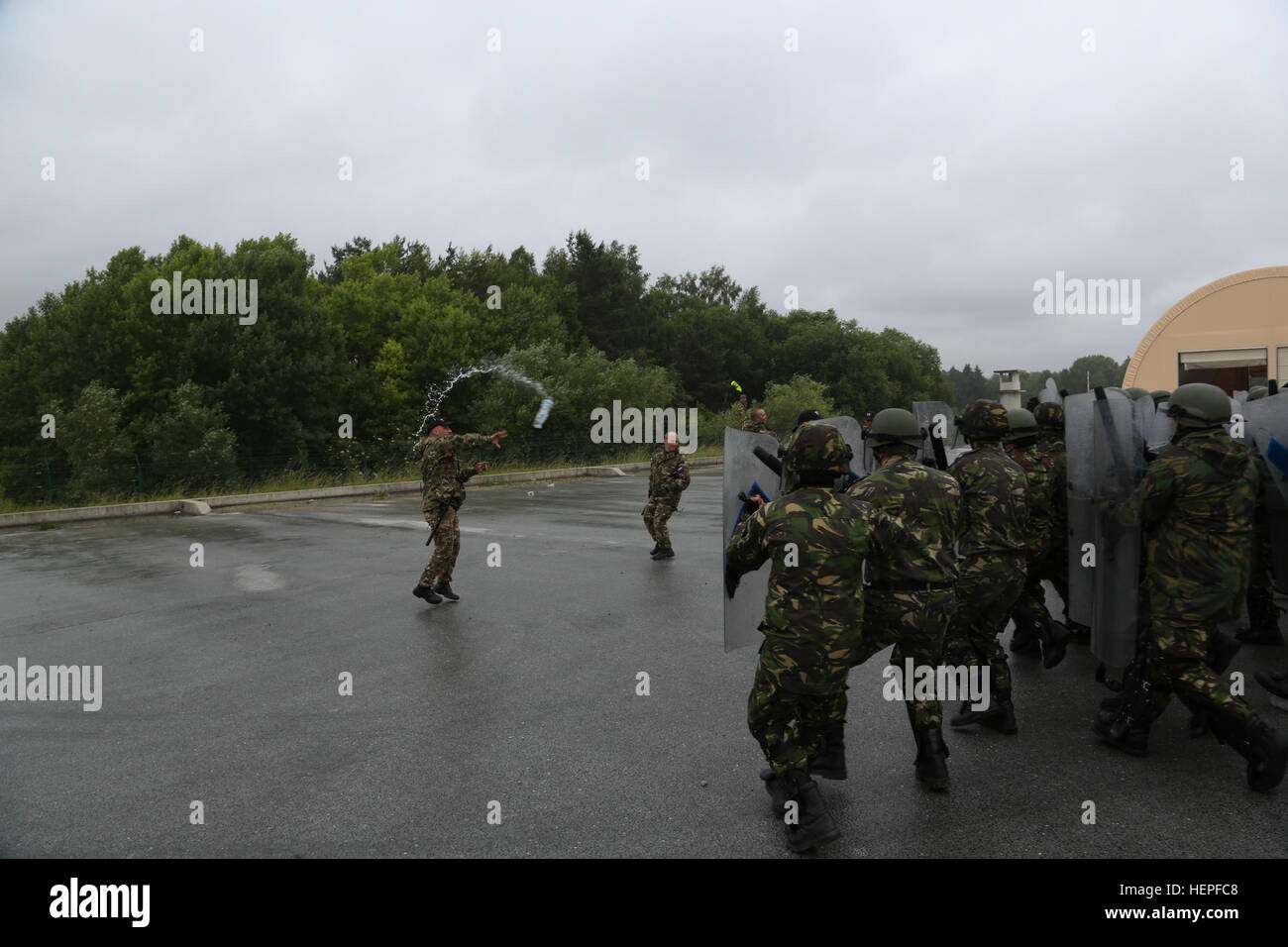 Soldats roumains, à droite, de la compagnie d'intervention régionale internationale, 26e Mountain, responsable de l'avant tandis que le slovène des soldats de la Police militaire slovène jeter des bouteilles d'eau à tester leur foule lutte anti-émeute (CRC) techniques tout en effectuant la formation du CRC lors d'une Force de paix au Kosovo (KFOR) de l'exercice de répétition de mission (MRE) au Centre de préparation interarmées multinationale à Hohenfels, Allemagne, le 18 juin 2015. La KFOR MRE est basé sur l'environnement opérationnel courant et est conçu pour préparer l'unité de maintien de la paix, de la stabilité, et des plans d'opérations au Kosovo à l'appui de authoritie civile Banque D'Images