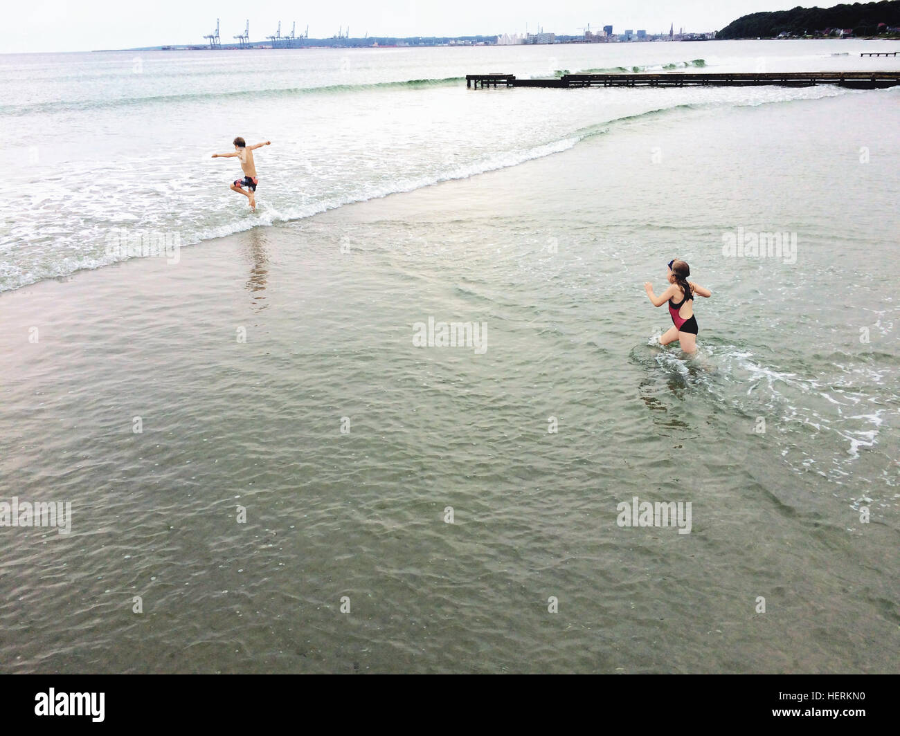 Garçon et fille courir en mer, Danemark Banque D'Images