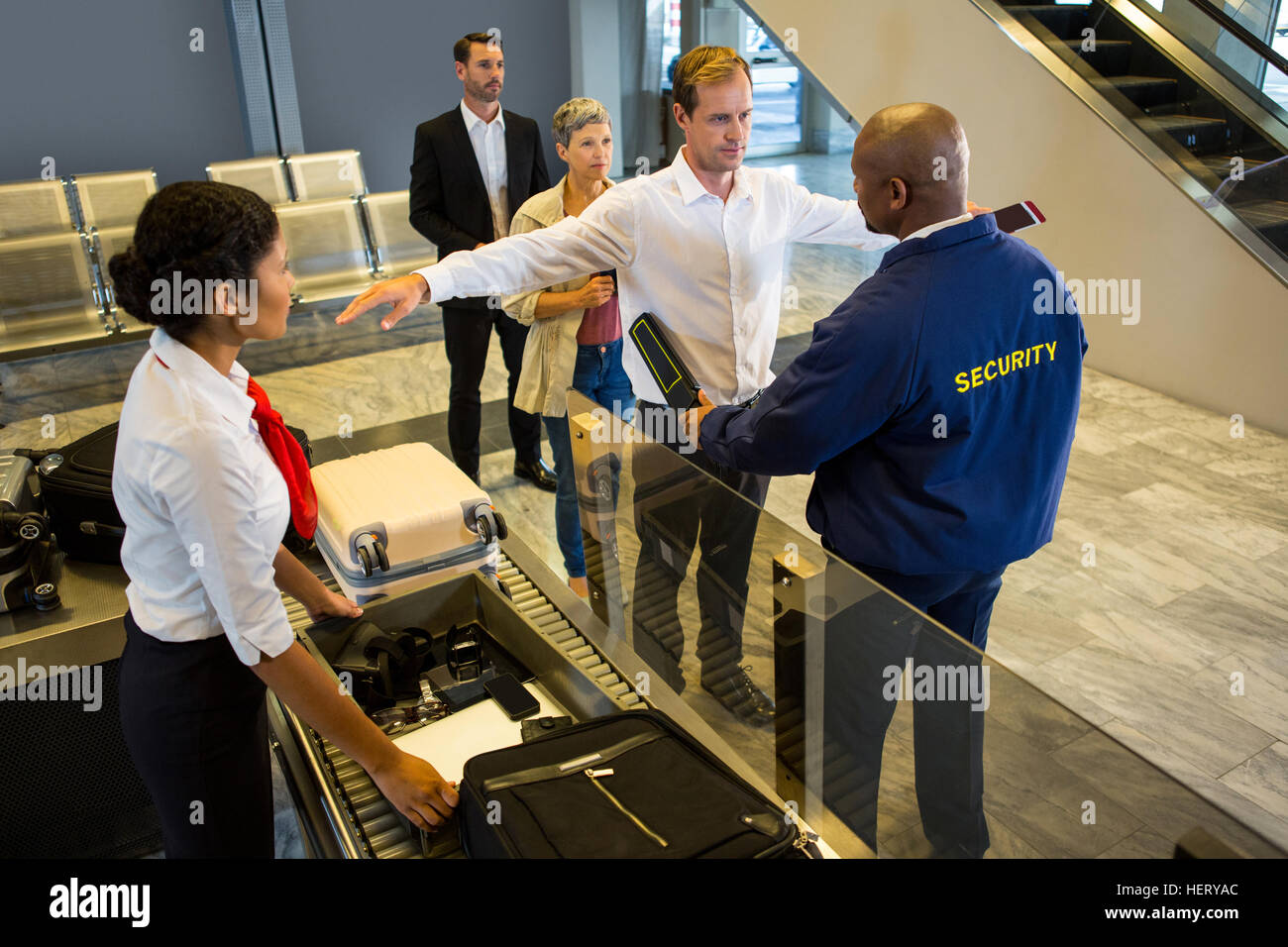 Security guard frisking passagers avec détecteur de métal à l'aéroport Banque D'Images