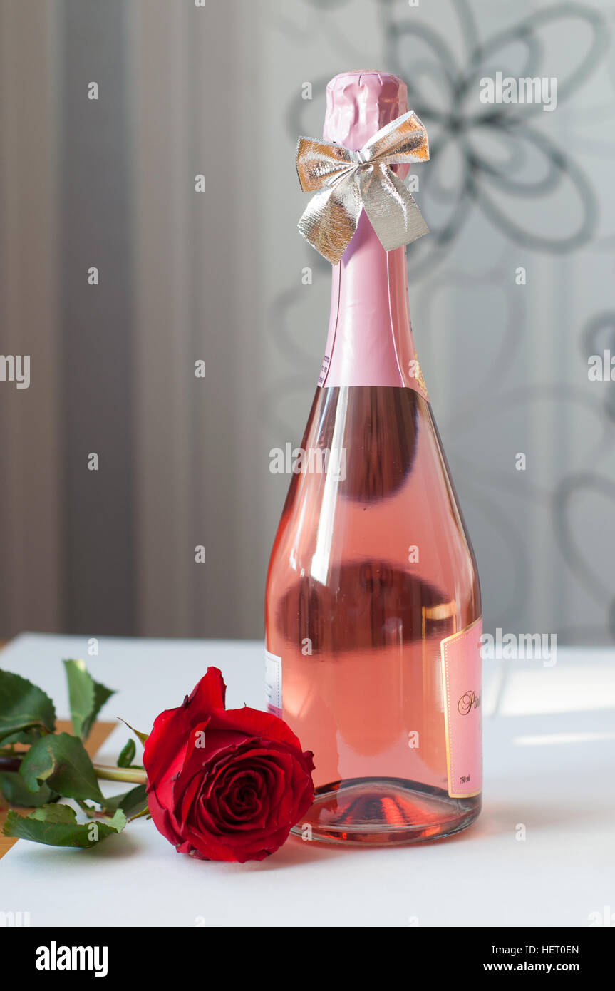Un champagne rose et une rose sur fond blanc Banque D'Images