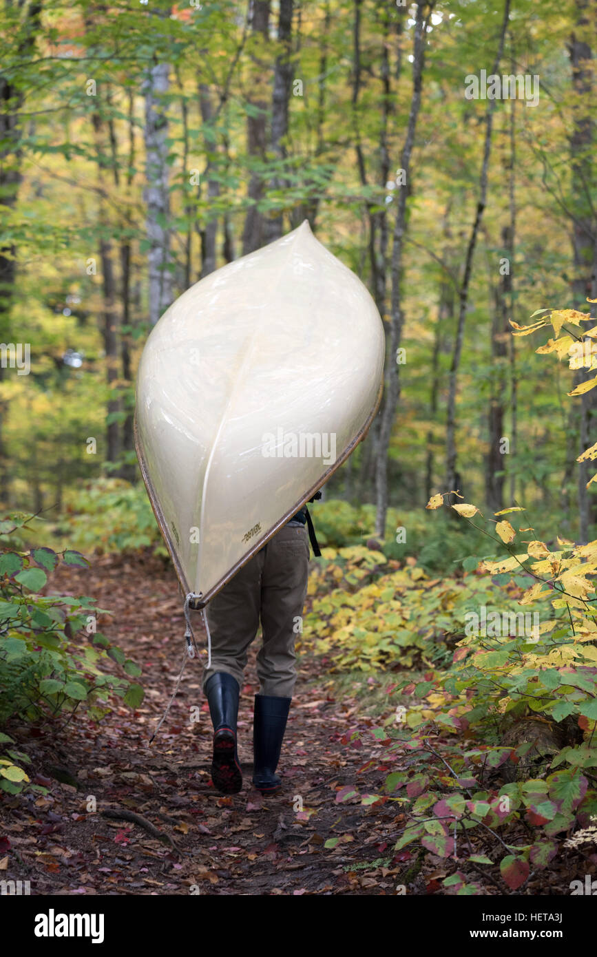 Portage d'un canot dans le St Regis Canoe Area d'Adirondack State Park, New York. Banque D'Images