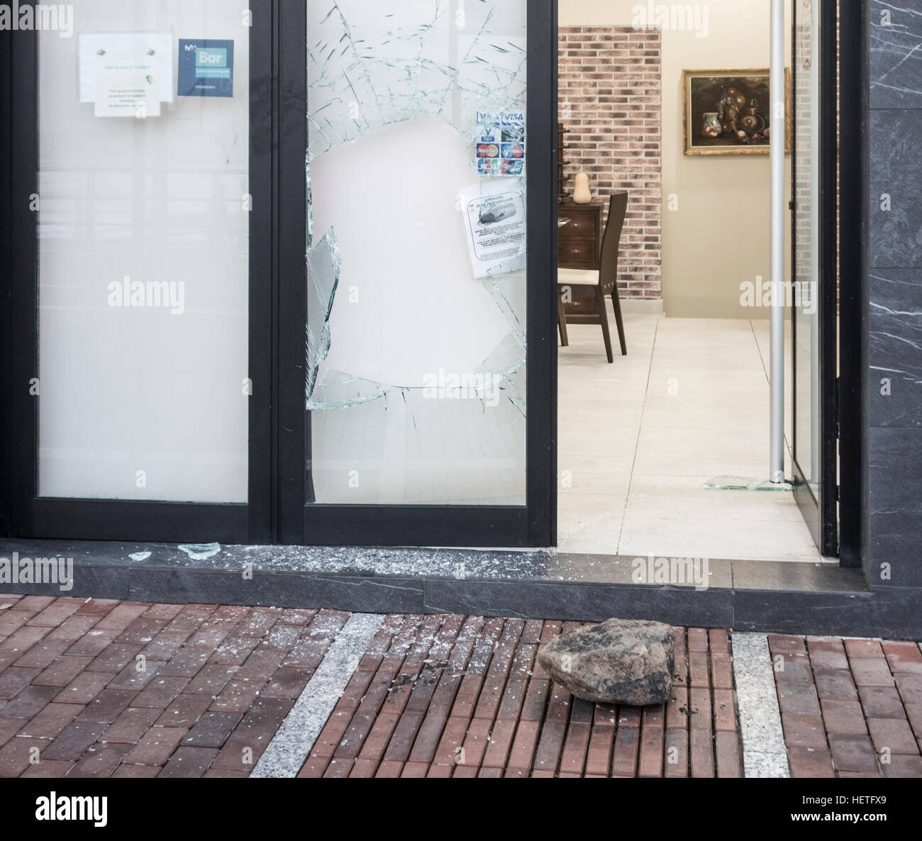 Gros rocher (en photo) à côté de la fenêtre/porte restaurant fracassées en Espagne Banque D'Images