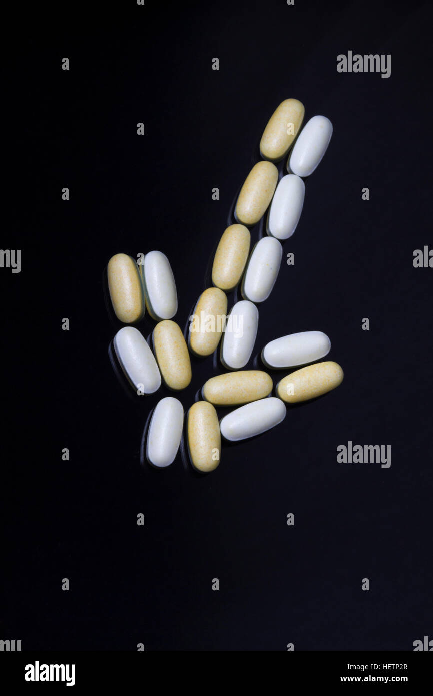 Comprimés de vitamine sur fond noir en forme de flèche Banque D'Images