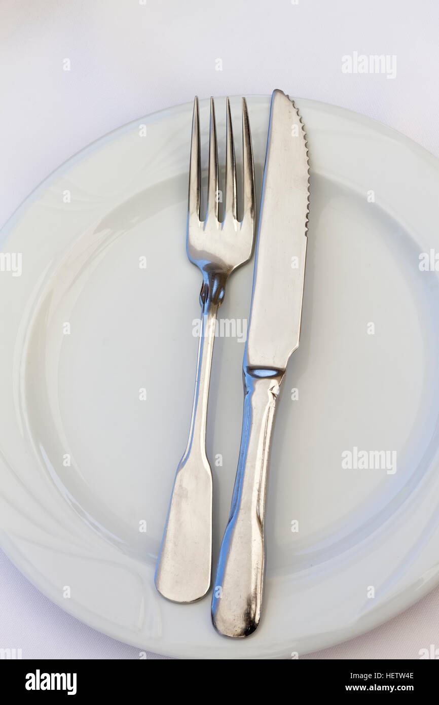 Le couteau et la fourchette sur l'assiette, isolé sur blanc. Close up. Banque D'Images