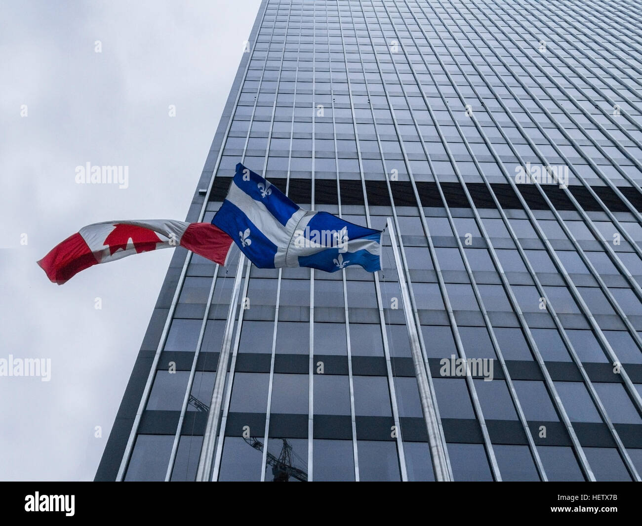 Les drapeaux canadien et québécois en face d'un skysrcaper Banque D'Images