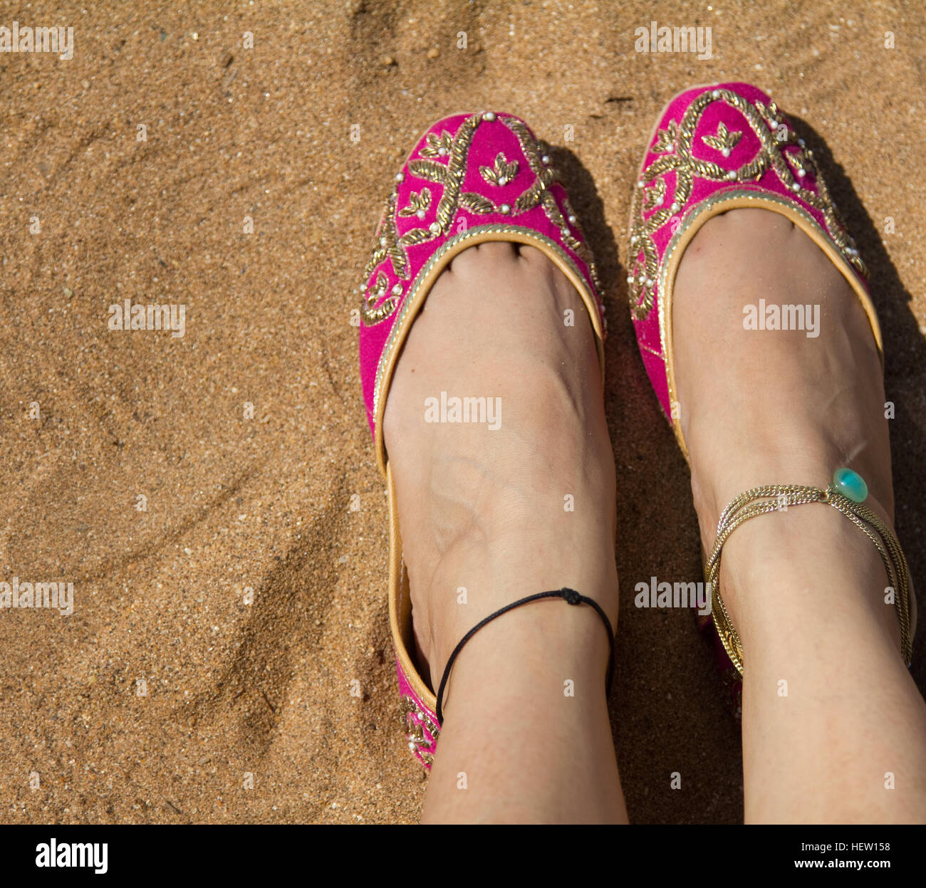 Une dame rose portant une paire de chaussures de femmes indiennes traditionnelles (jutis) à la plage d'Anjuna à Goa, Inde Banque D'Images