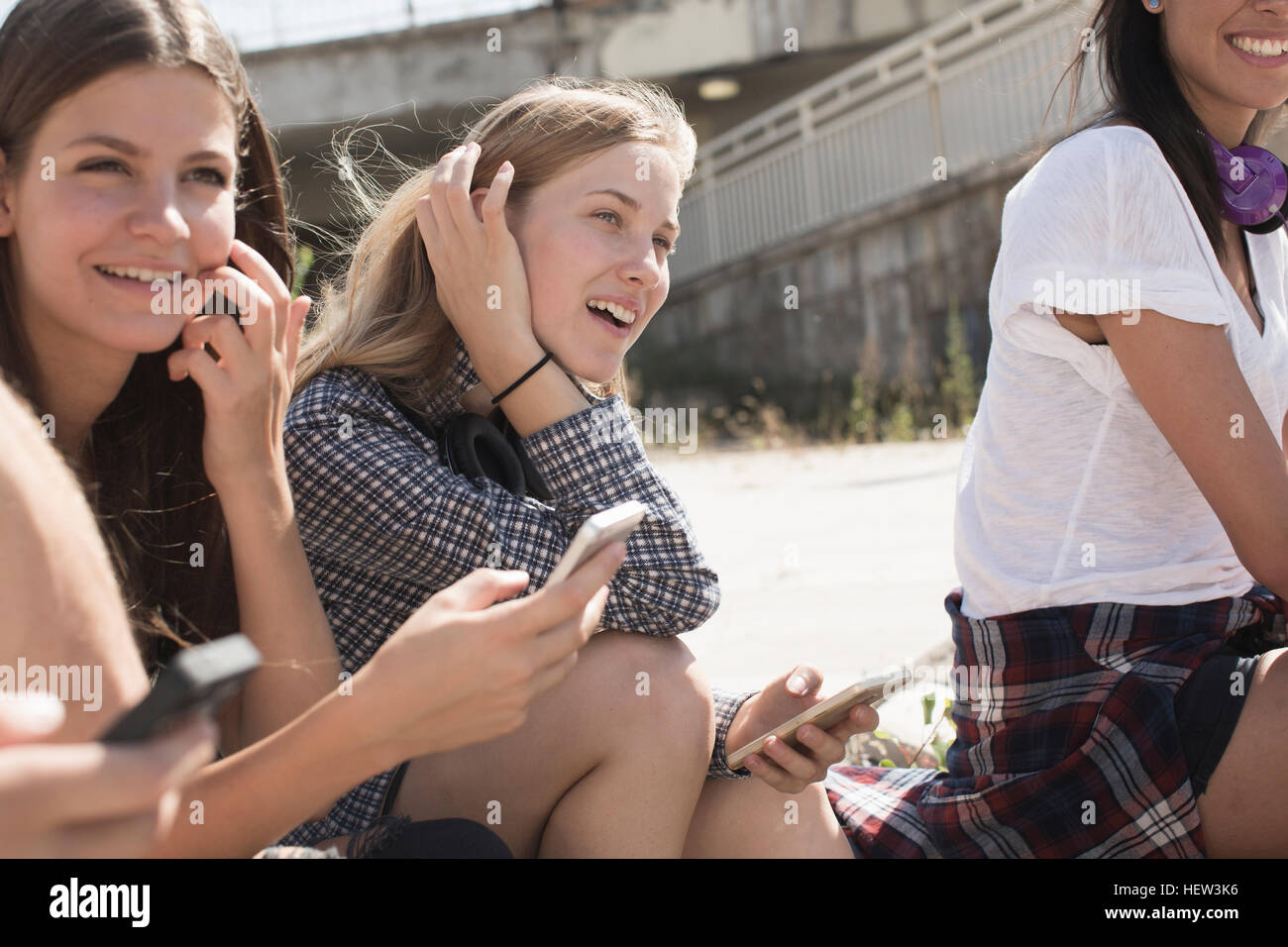 Friends sitting together using smartphones Banque D'Images