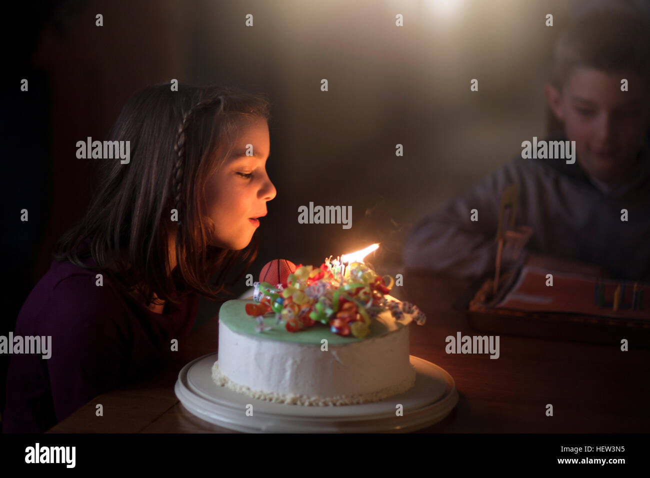 Girl blowing out candles on cake Banque D'Images
