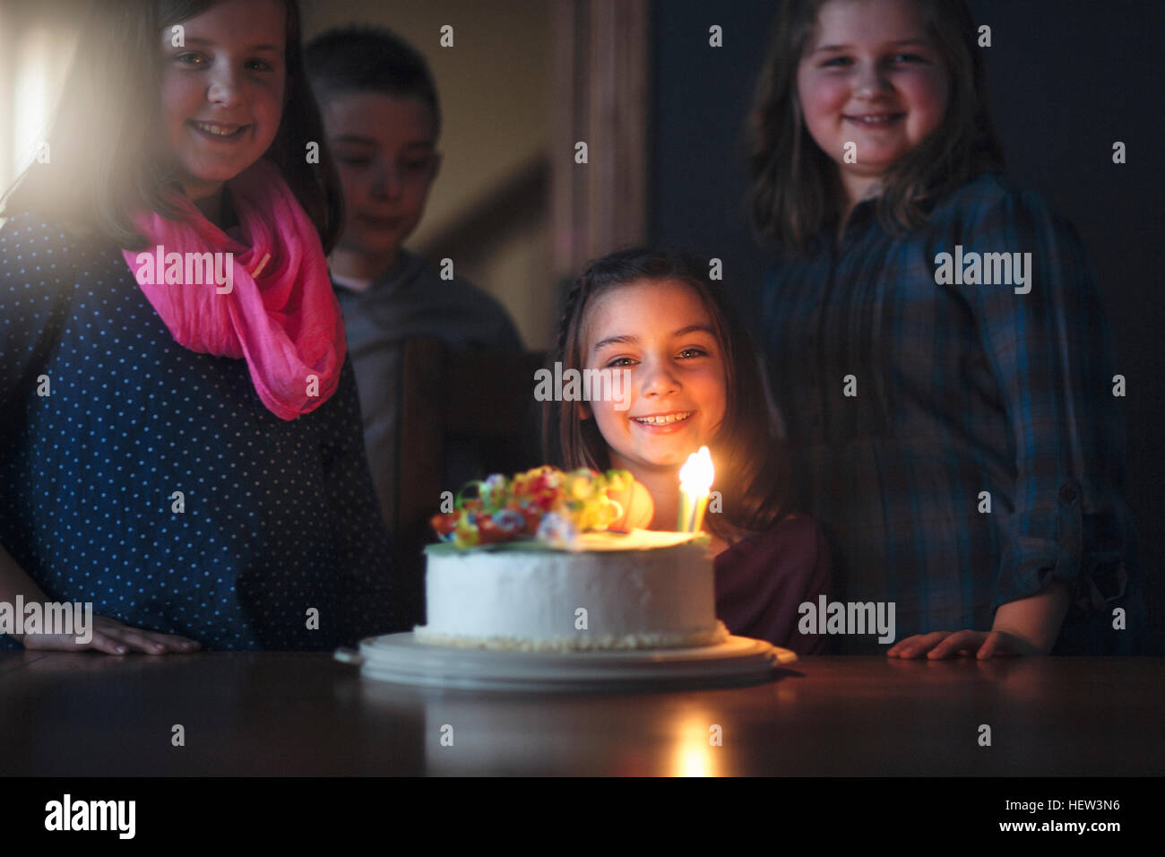 Fille avec gâteau d'anniversaire entouré d'amis Banque D'Images