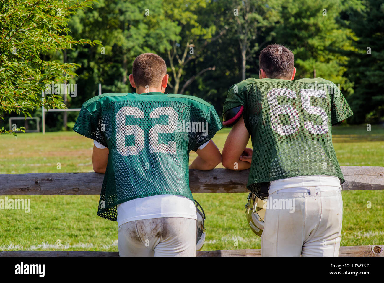 Vue arrière de deux jeunes joueurs de football américain s'appuyant sur jeu fence Banque D'Images