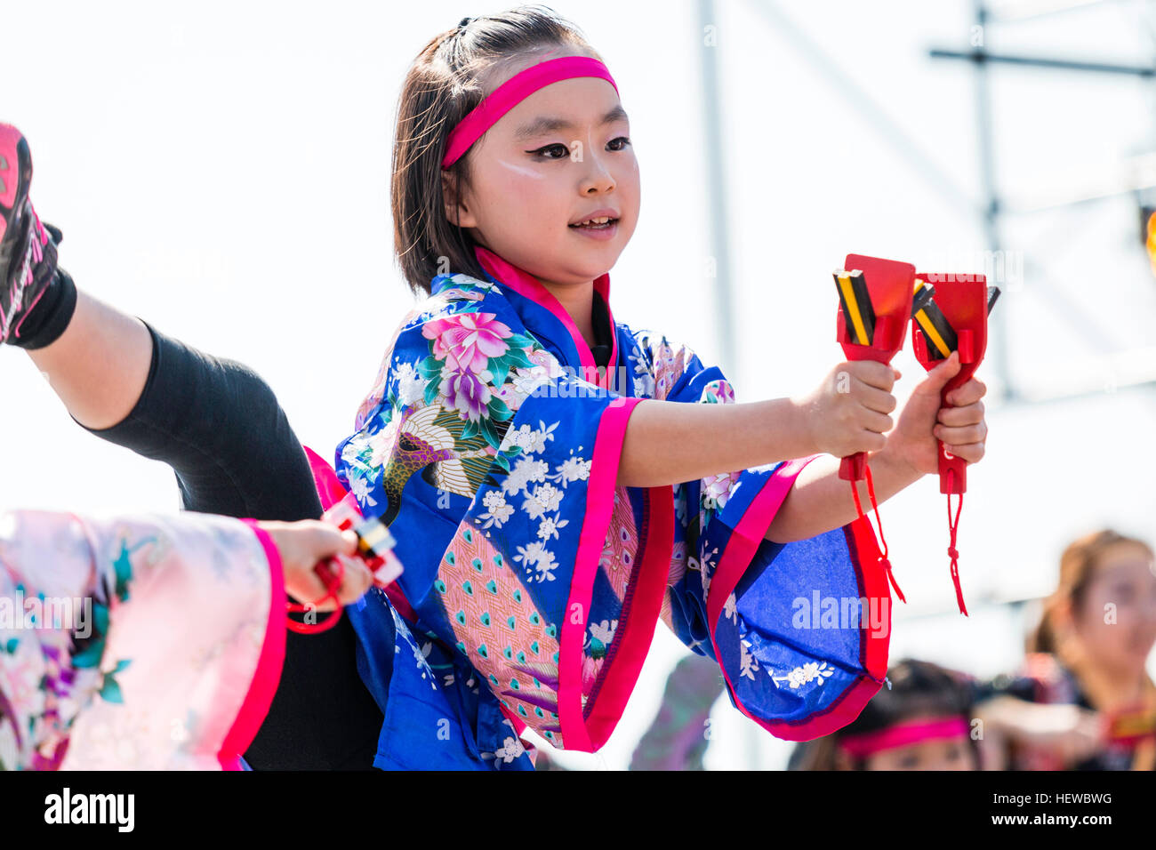 Yosakoi Festival japonais. Enfant, jeune fille, la danse dans le cadre d'équipe, porte des yukata traditionnel veste, holding naruko, battants en bois, dans chaque main. Banque D'Images