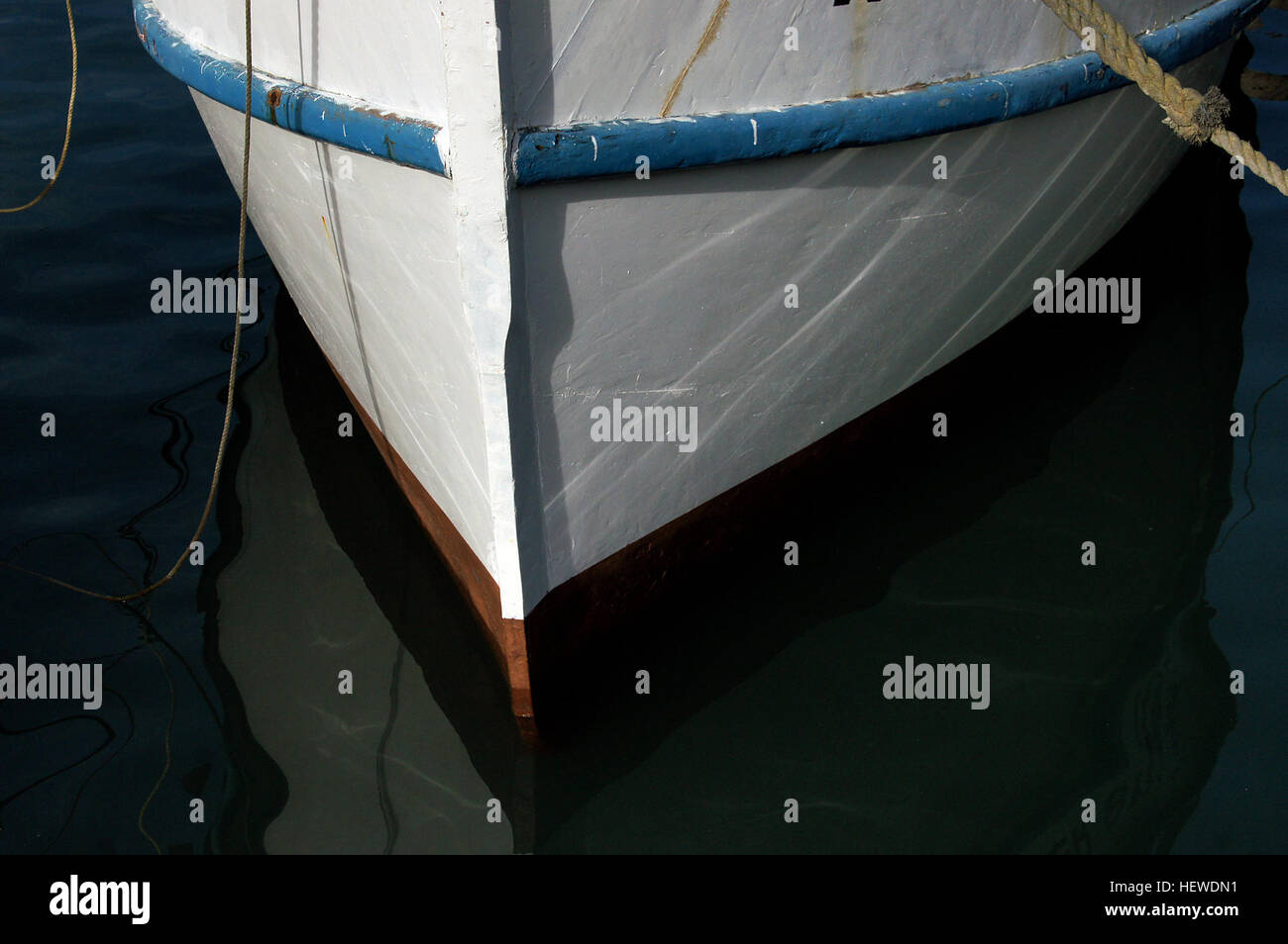 Cette image montre un bateau de pêche blanc et bleu avec sa coque et sa proue mises en évidence. La photo capture l'extrémité avant du bateau amarré à une marina, illustrant les caractéristiques du bateau dans un cadre maritime. Banque D'Images