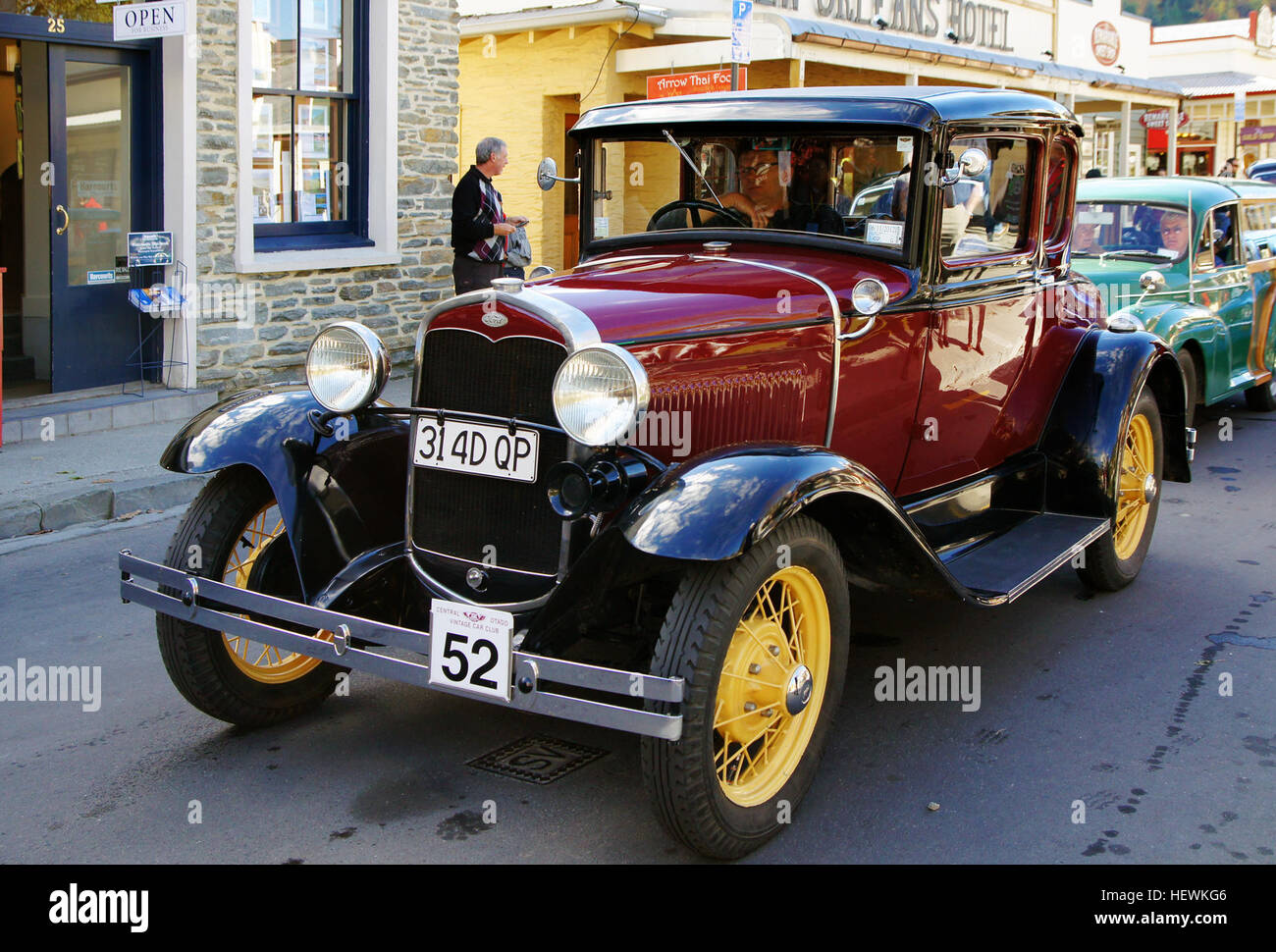 L'image capture le vibrant festival d'automne à Arrowtown, en Nouvelle-Zélande, avec un défilé de voitures anciennes avec des voitures anciennes et restaurées. L'un des points forts de l'événement est la Ford rouge et les voitures avec des roues jaunes à rayons métalliques, mettant en valeur le charme historique de la région et l'attrait intemporel des automobiles classiques. Banque D'Images