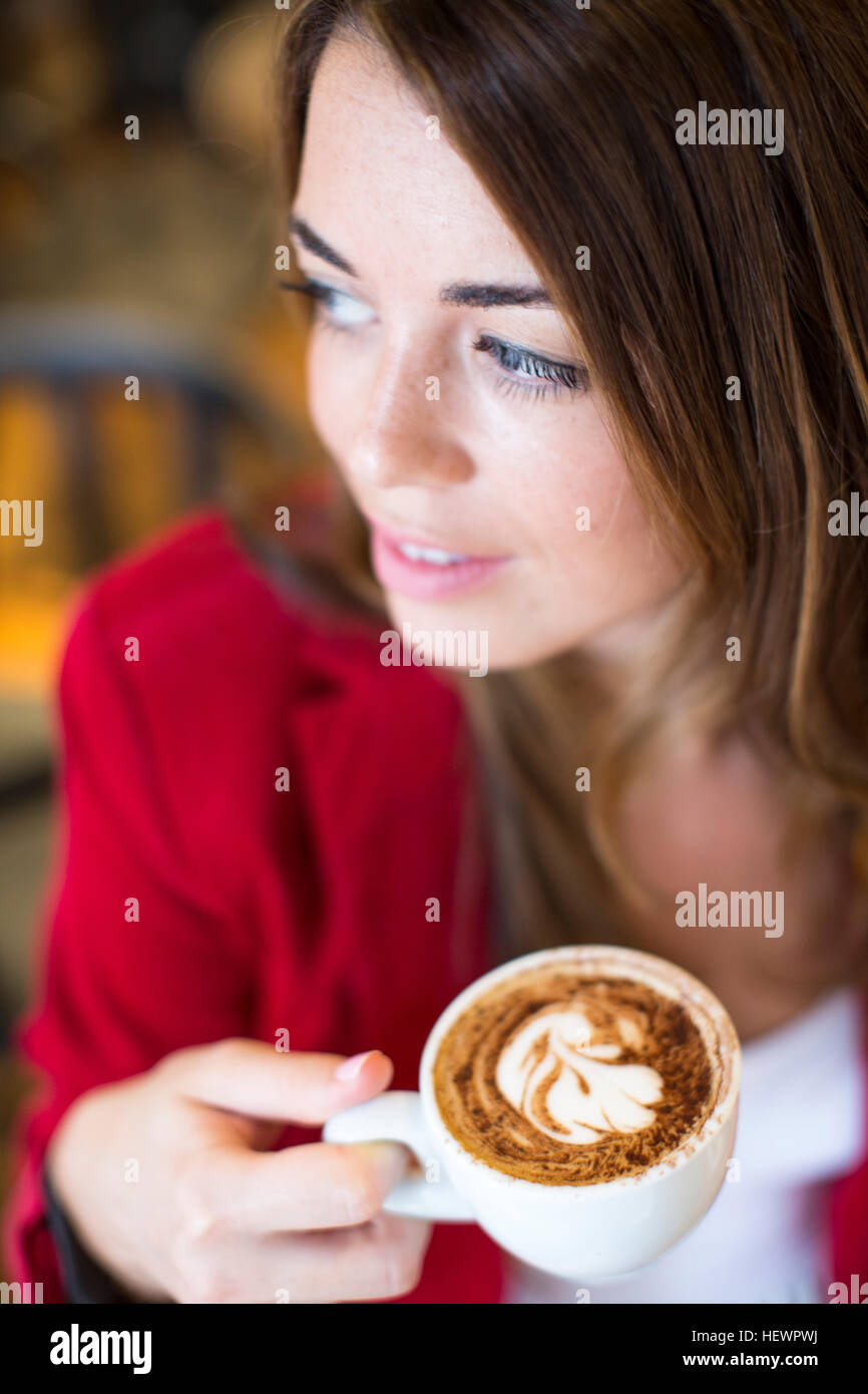 Close up of young woman with cappuccino au café Banque D'Images