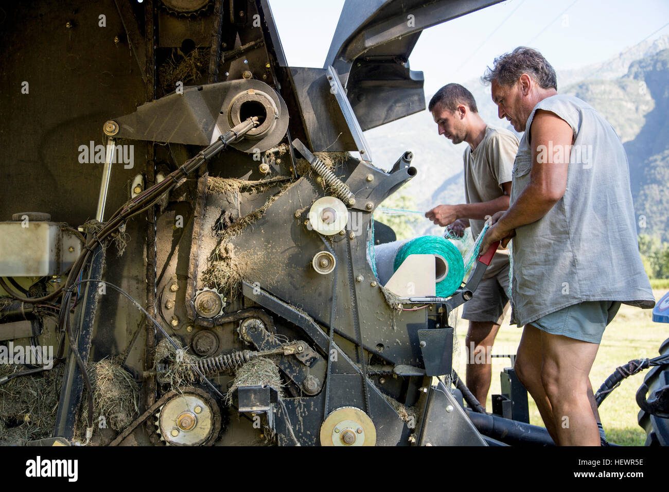 Deux hommes farmworkers démêler la compensation dans la ramasseuse-presse à foin Banque D'Images