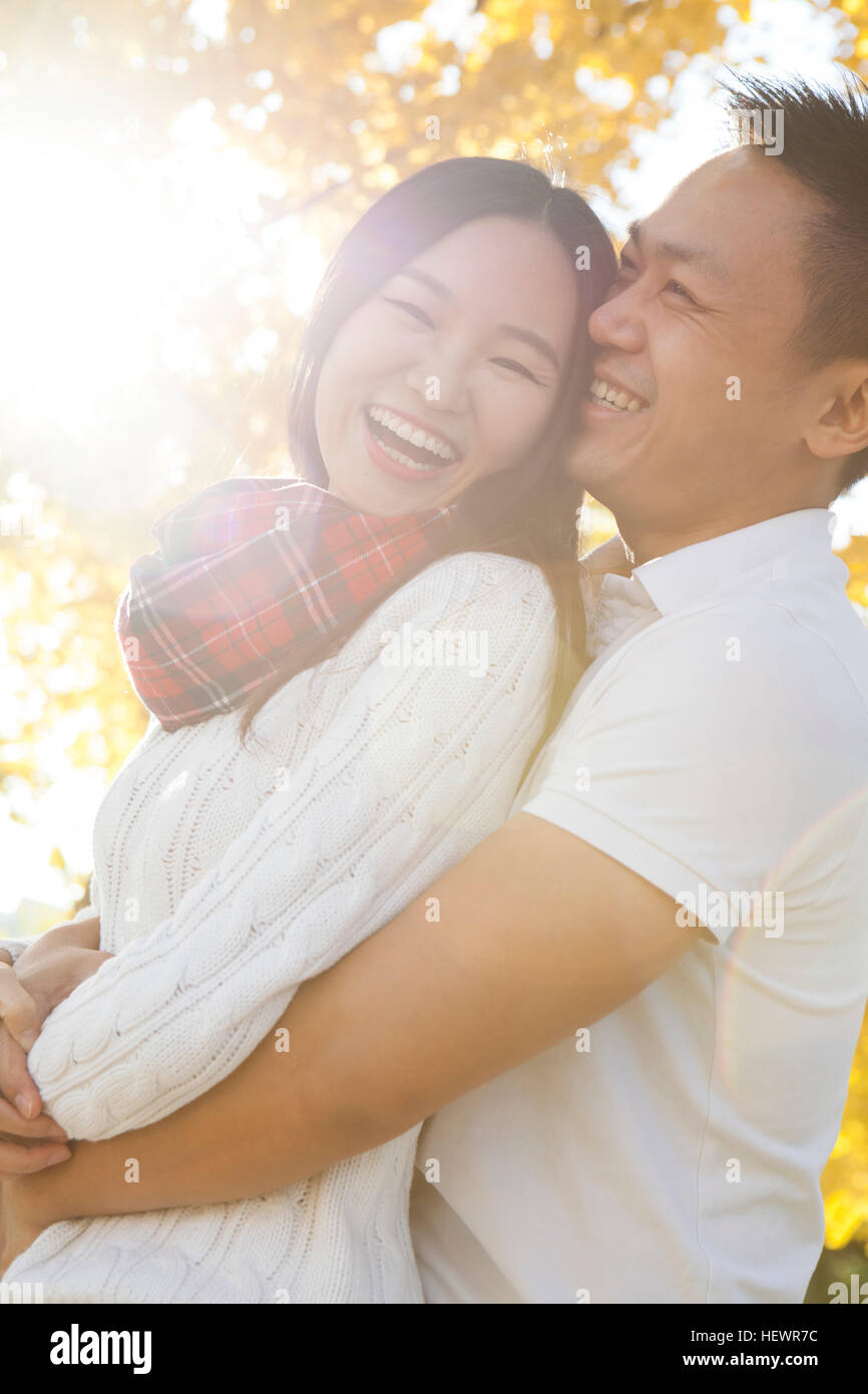 Jeune couple hugging in sunlit autumnal park, Beijing, Chine Banque D'Images