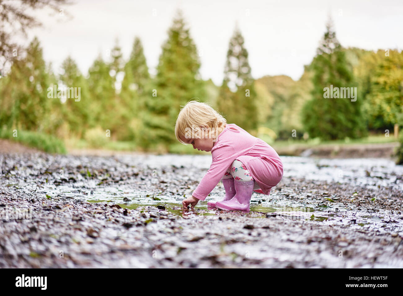 Baby Girl wearing rubber boots jouant dans la boue flaque Banque D'Images
