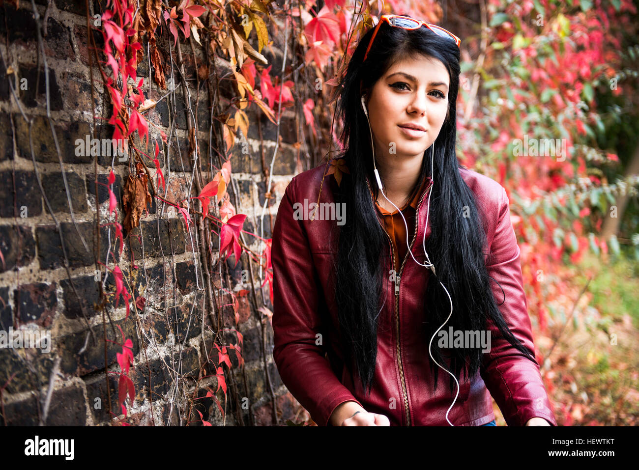 Portrait de jeune femme assise à l'extérieur, wearing earphones Banque D'Images