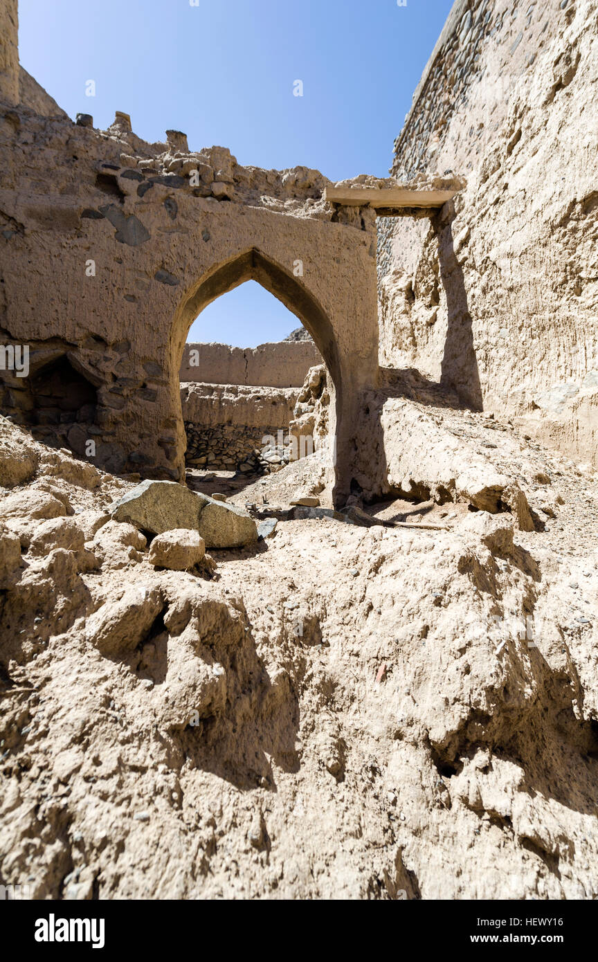 Brique de boue orné d'arcades et les portes au-dessus de décombres s'effondrer dans un village abandonné dans le désert. Banque D'Images