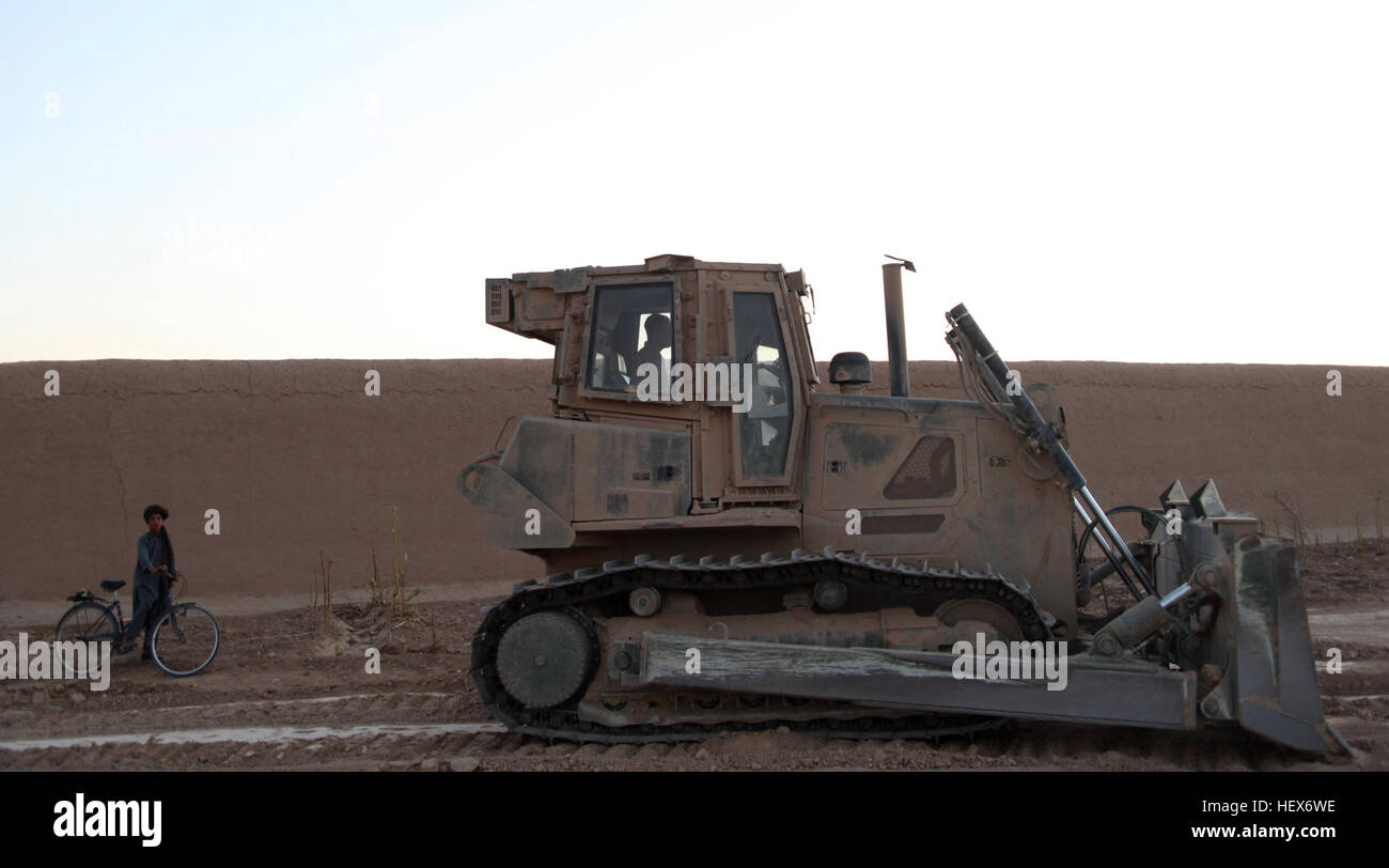 MUSA QALEH, province de Helmand, République islamique d'Afghanistan - un garçon afghan s'arrête derrière un bulldozer exploité par Lance Cpl. Robert Nickum, 24 ans, opérateur d'équipement lourd de Colorado Springs, au Colorado, à un petit poste de combat dans la région de Musa Qaleh, le 3 novembre 2010. Des ingénieurs en génie de combat 1er Bataillon, 1re Division de marines (avant), utilisé le bulldozer pour pousser de grandes quantités de saleté dans des piles de la création d'un grand burm qui encerclait la position occupée par le 1er Bataillon, 8e Régiment de Marines. (U.S. Marine Corps photo par le Cpl. John M. McCall) Ingénieurs d'améliorer la défense de 1-8dans Musa Qal'eh DVIDS338911 Banque D'Images