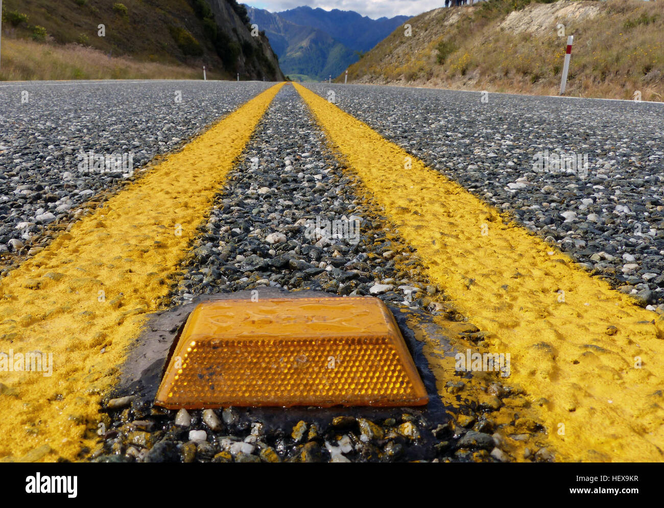 Les yeux de chat jaunes, ou marqueurs de chaussée surélevés rétroréfléchissants (RRPM), sont placés le long des routes pour renforcer les lignes interdites de passage, améliorant ainsi la visibilité, en particulier sur les routes mouillées. Ils aident les conducteurs à identifier les zones d'accès restreint et sont placés tous les 10 mètres sur les routes rurales non éclairées pour des raisons de sécurité. Banque D'Images